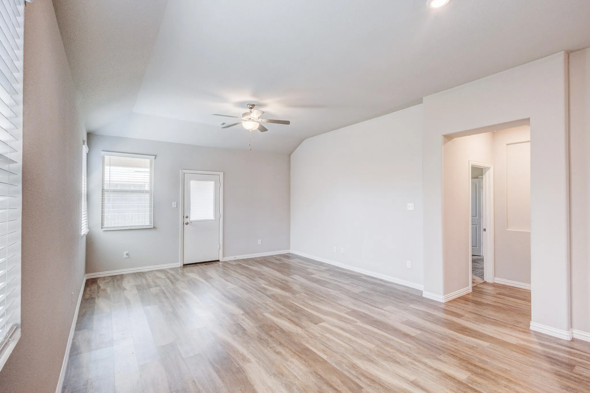 Spacious room featuring wood-finish flooring, a ceiling fan, and recessed lighting