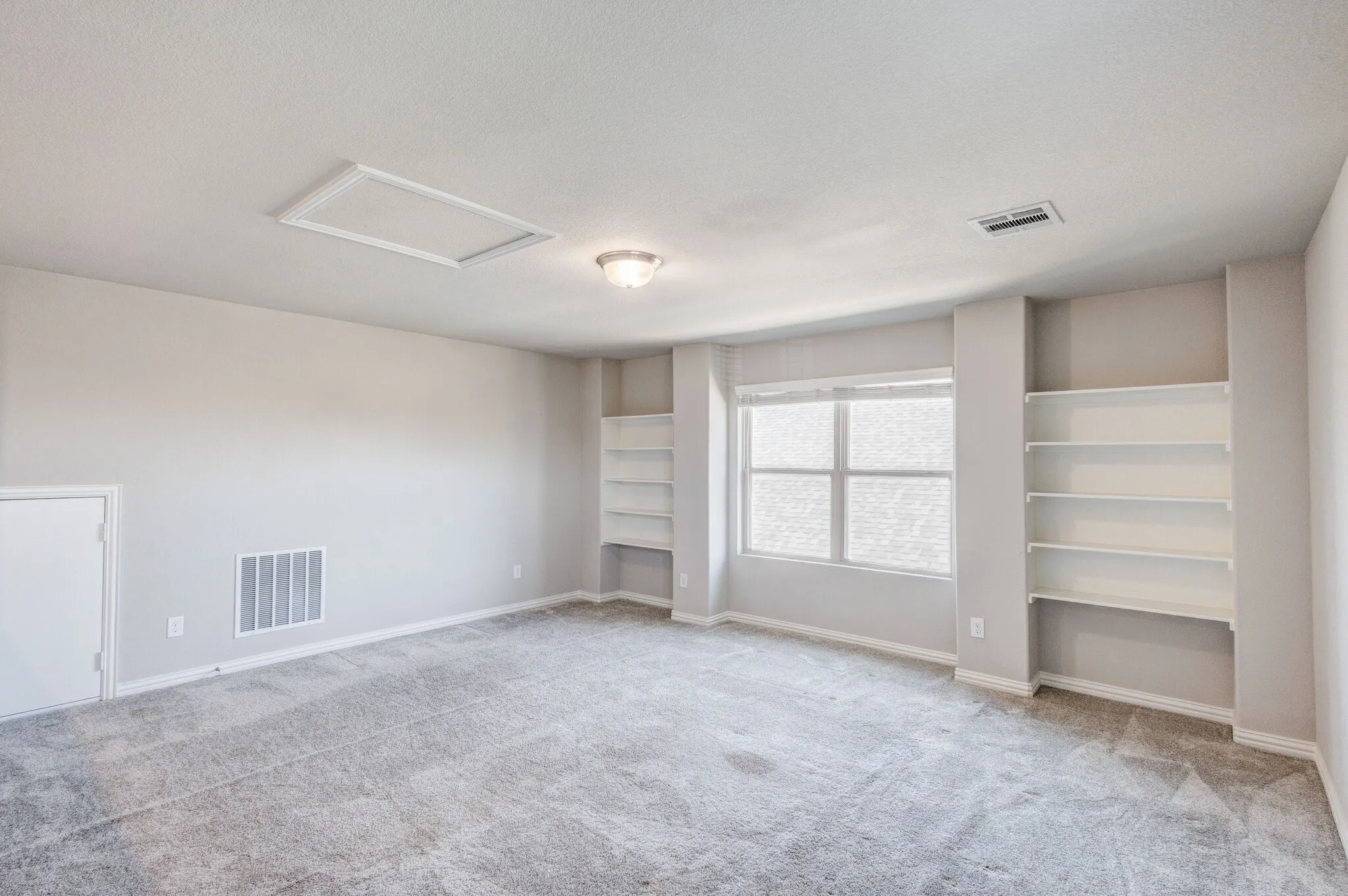 Recessed built-in shelving, gray carpet, flush-mount ceiling light fixture, and window with blinds