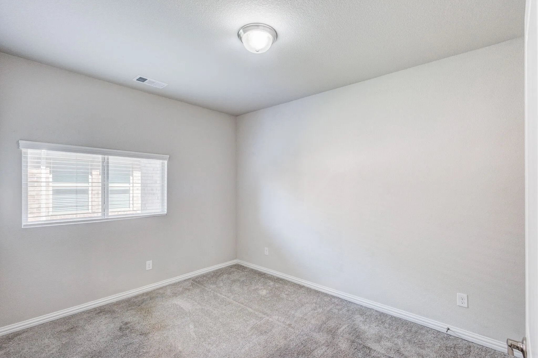 Recessed window with blinds, ceiling-mounted light fixture, and neutral wall paint