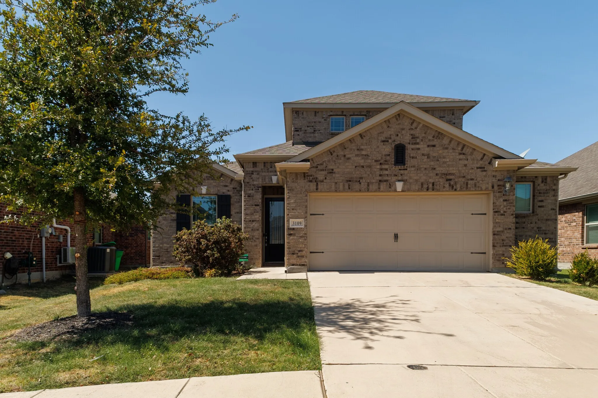 Brick exterior with a gabled roofline, two-car garage, and driveway