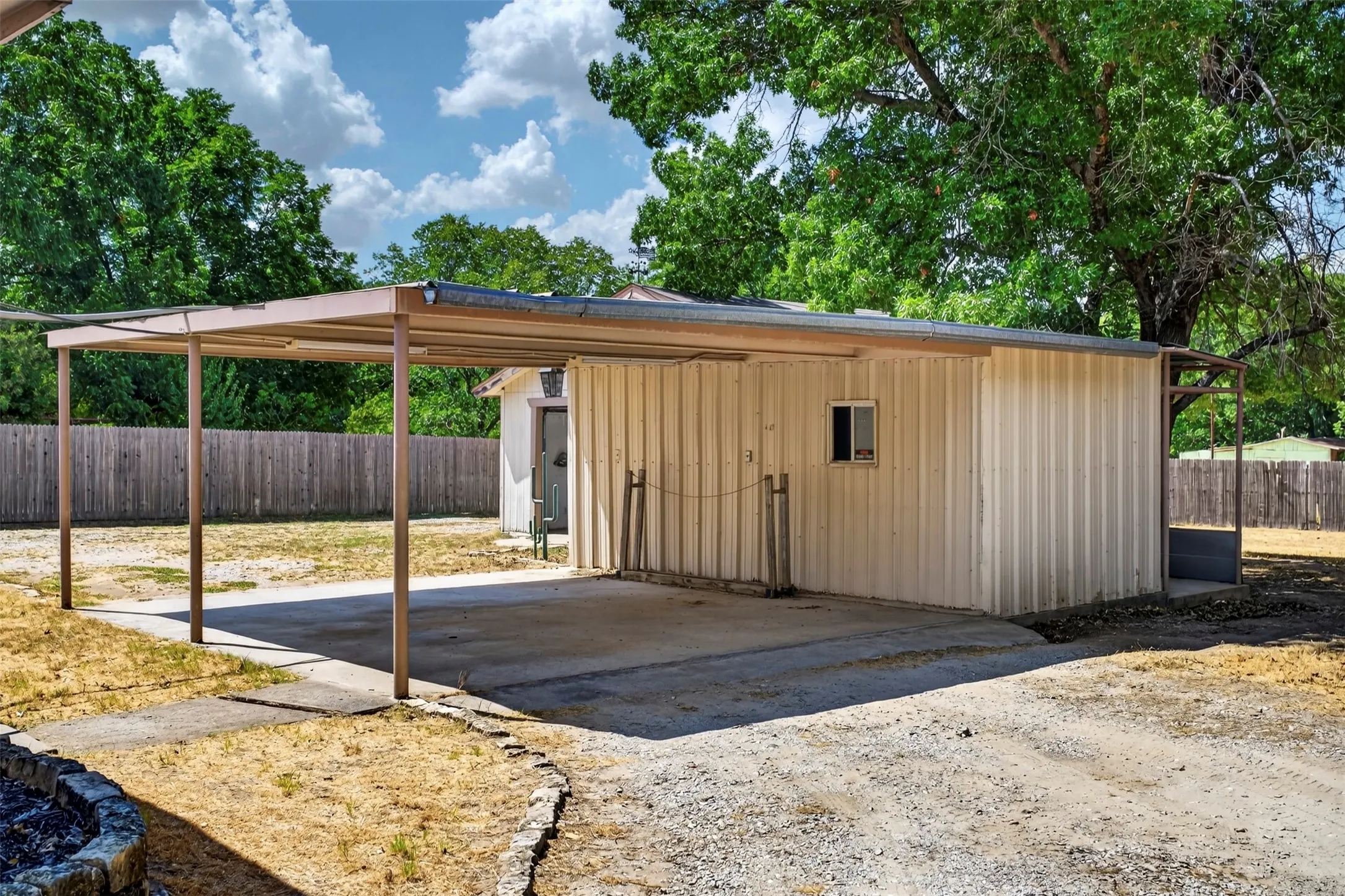Detached metal building with a single window and an attached carport