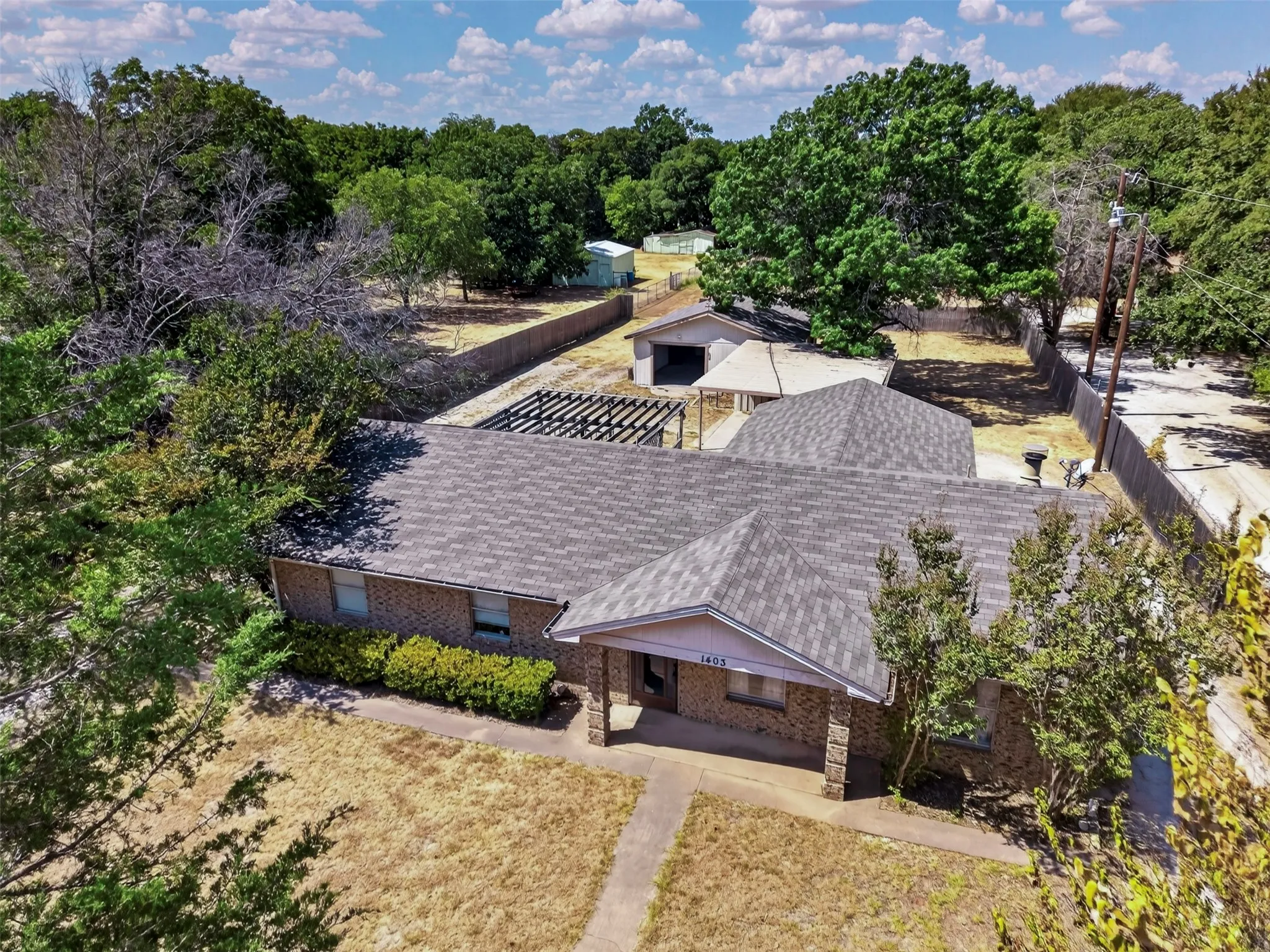 Brick exterior, covered front entry, established perimeter fencing, mature trees, and detached garage structure