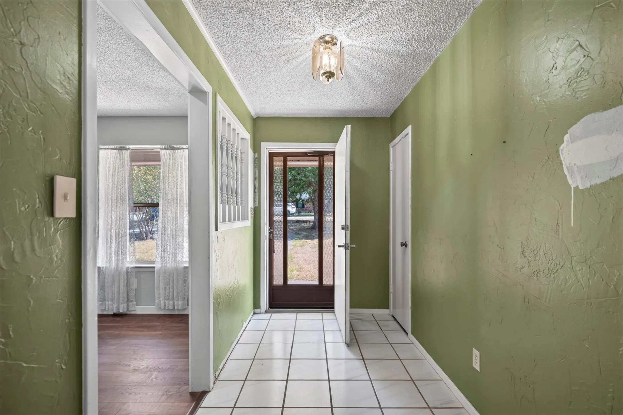 Entryway featuring white tile flooring and a glass-paneled front door