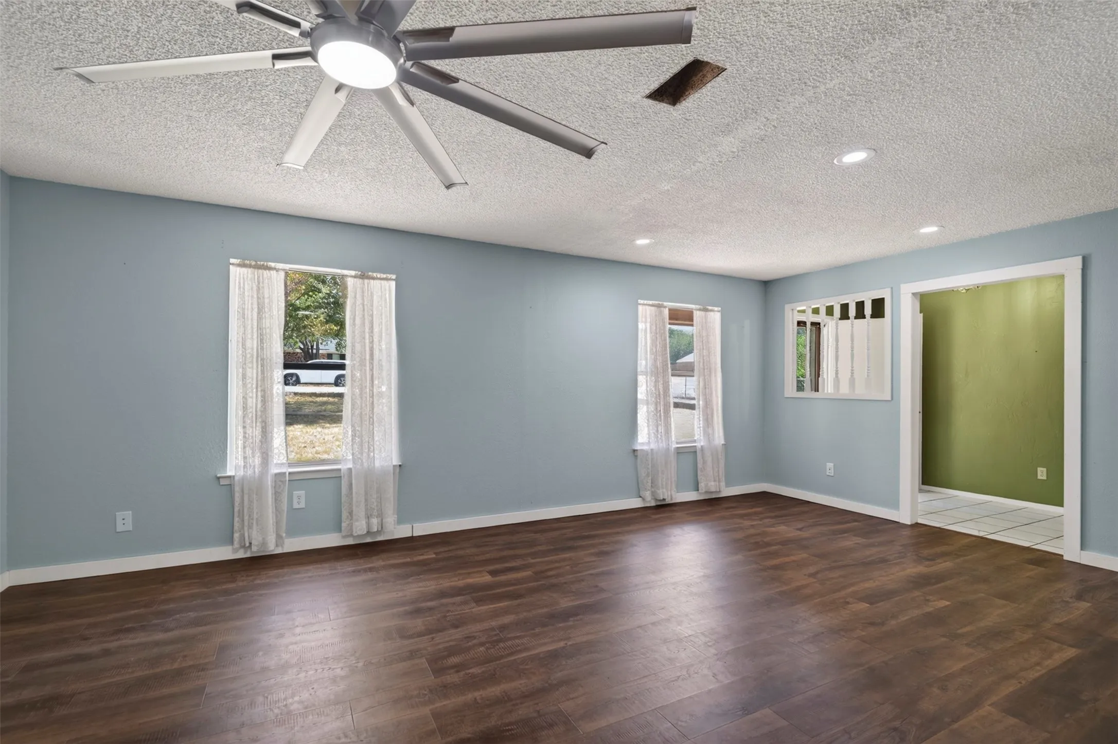 Expansive room featuring wood-finish flooring, light blue walls, and a contemporary ceiling fan