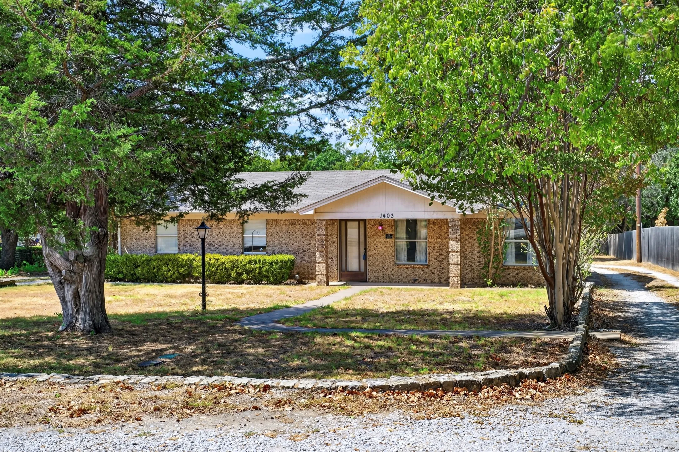 Brick exterior with a covered entry, gabled roofline, and established landscaping