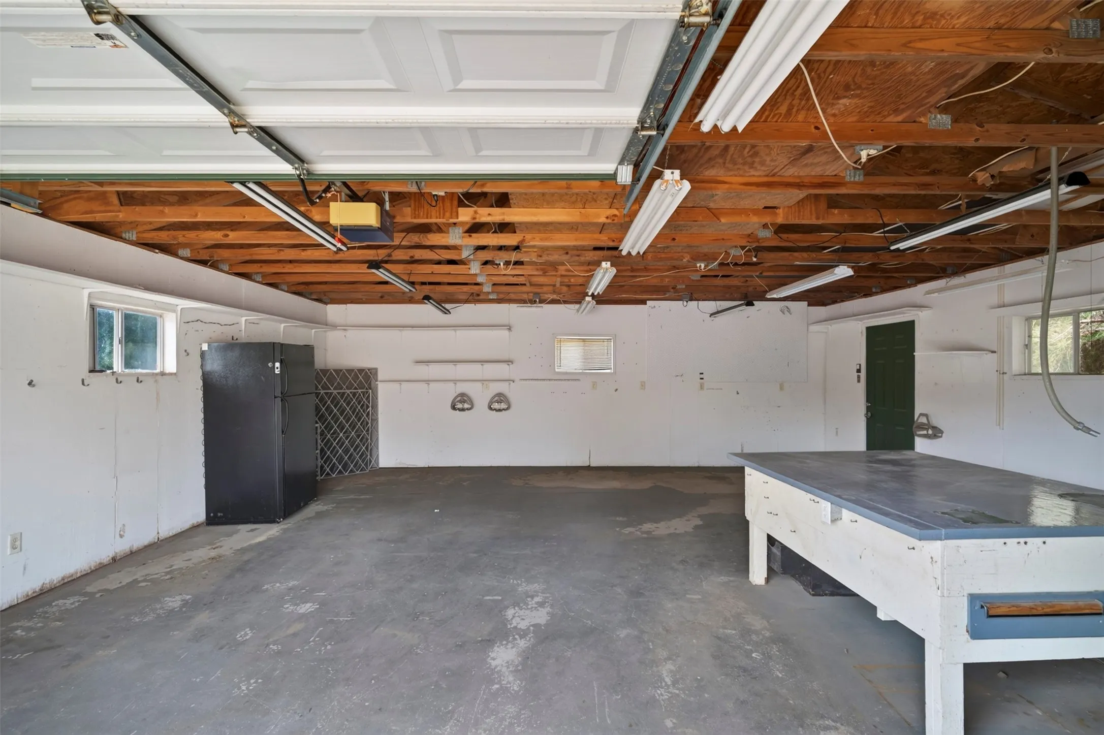 Spacious garage with concrete flooring, exposed wood beam ceiling, and multiple windows