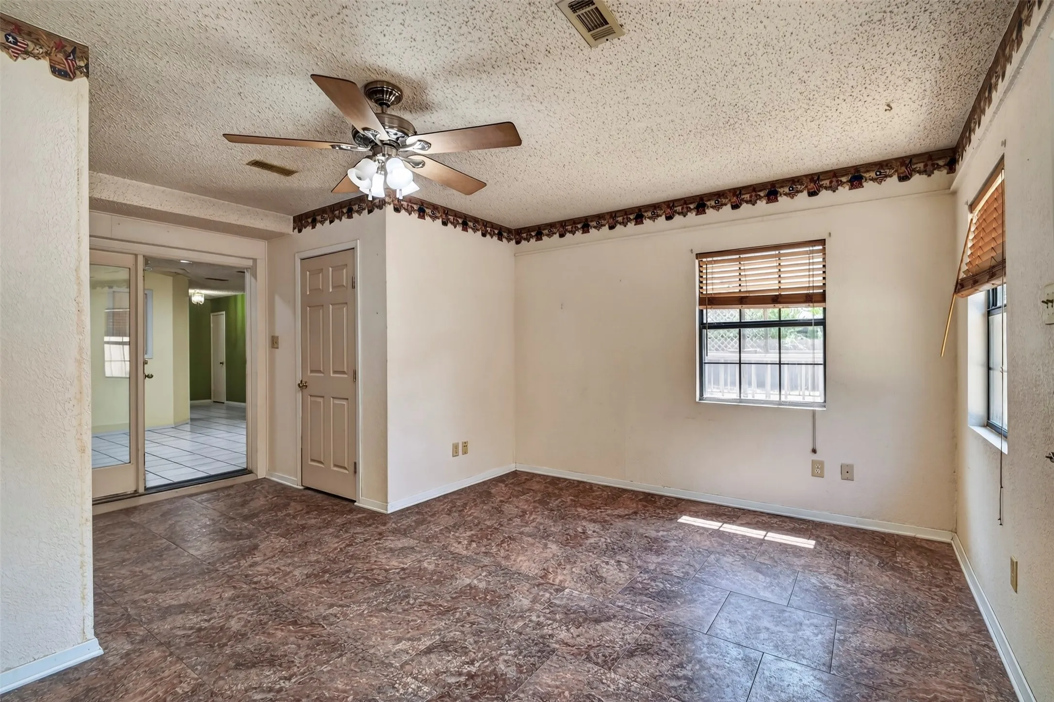 Wood-look flooring, ceiling fan with light fixture, sliding glass doors, and multiple windows