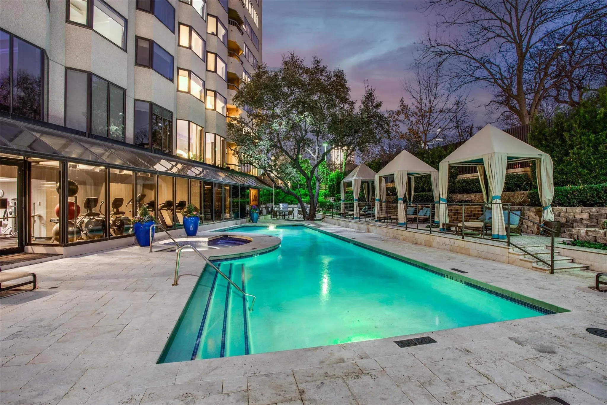 Swimming pool with integrated spa, adjacent to a fitness center with expansive windows