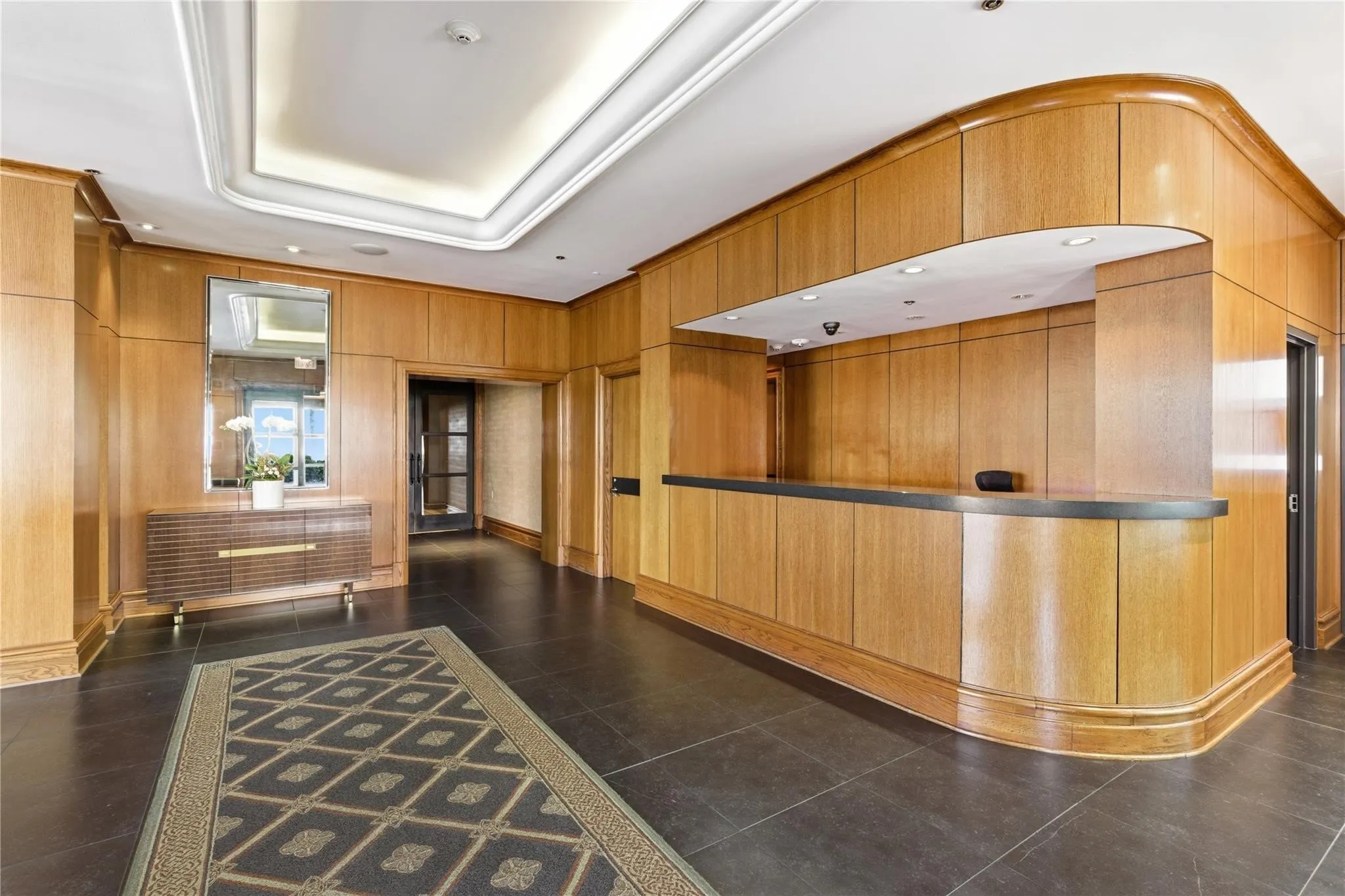 Wood paneling throughout, dark tile flooring, recessed lighting, and a tray ceiling