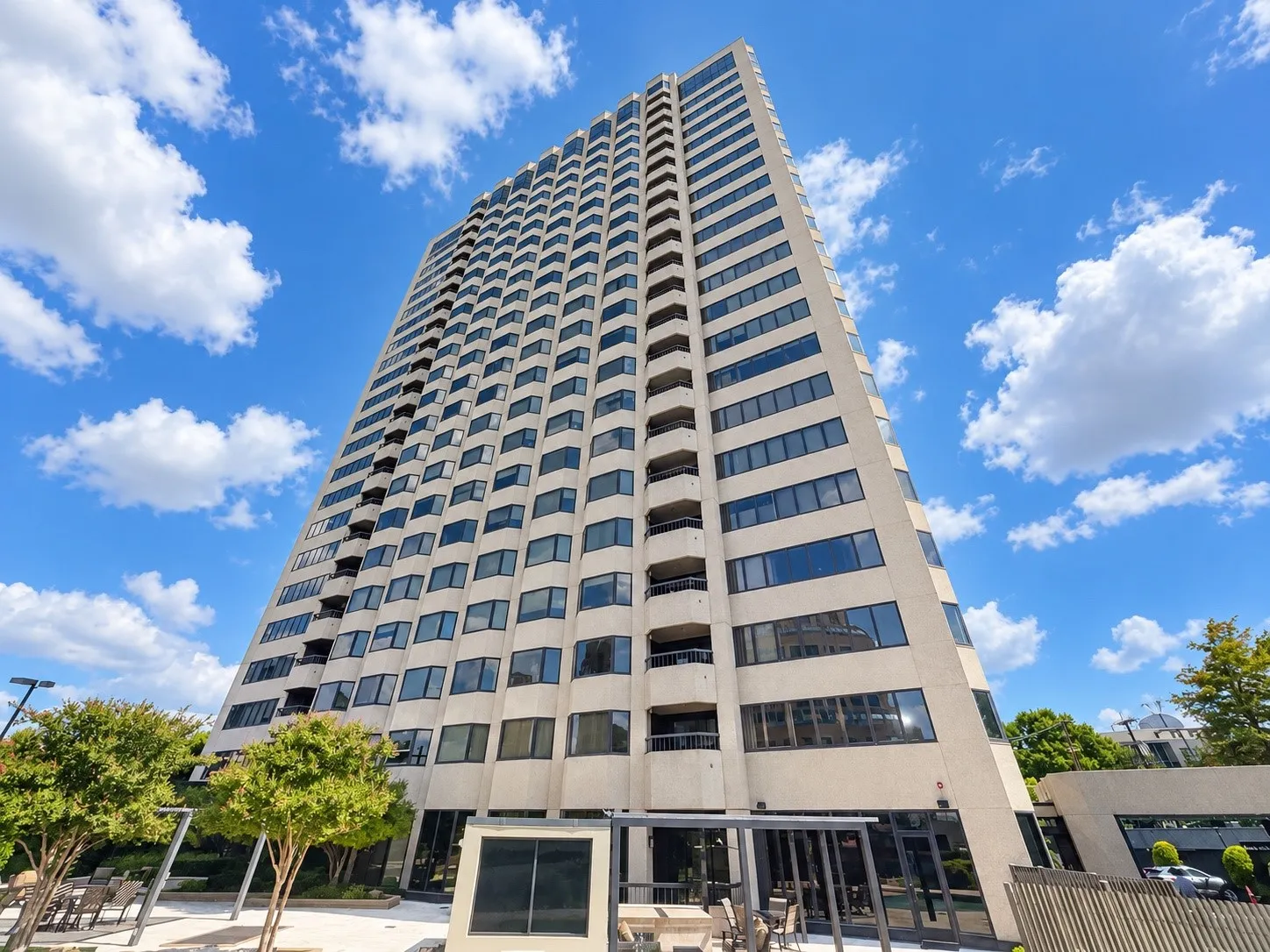 High-rise building with a light-colored facade, multiple balconies, and dark-framed windows