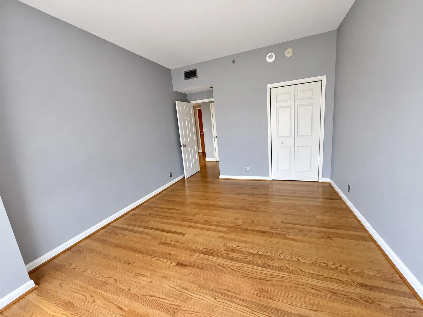 Hardwood flooring, painted walls, white trim, bi-fold closet doors, and a paneled interior door