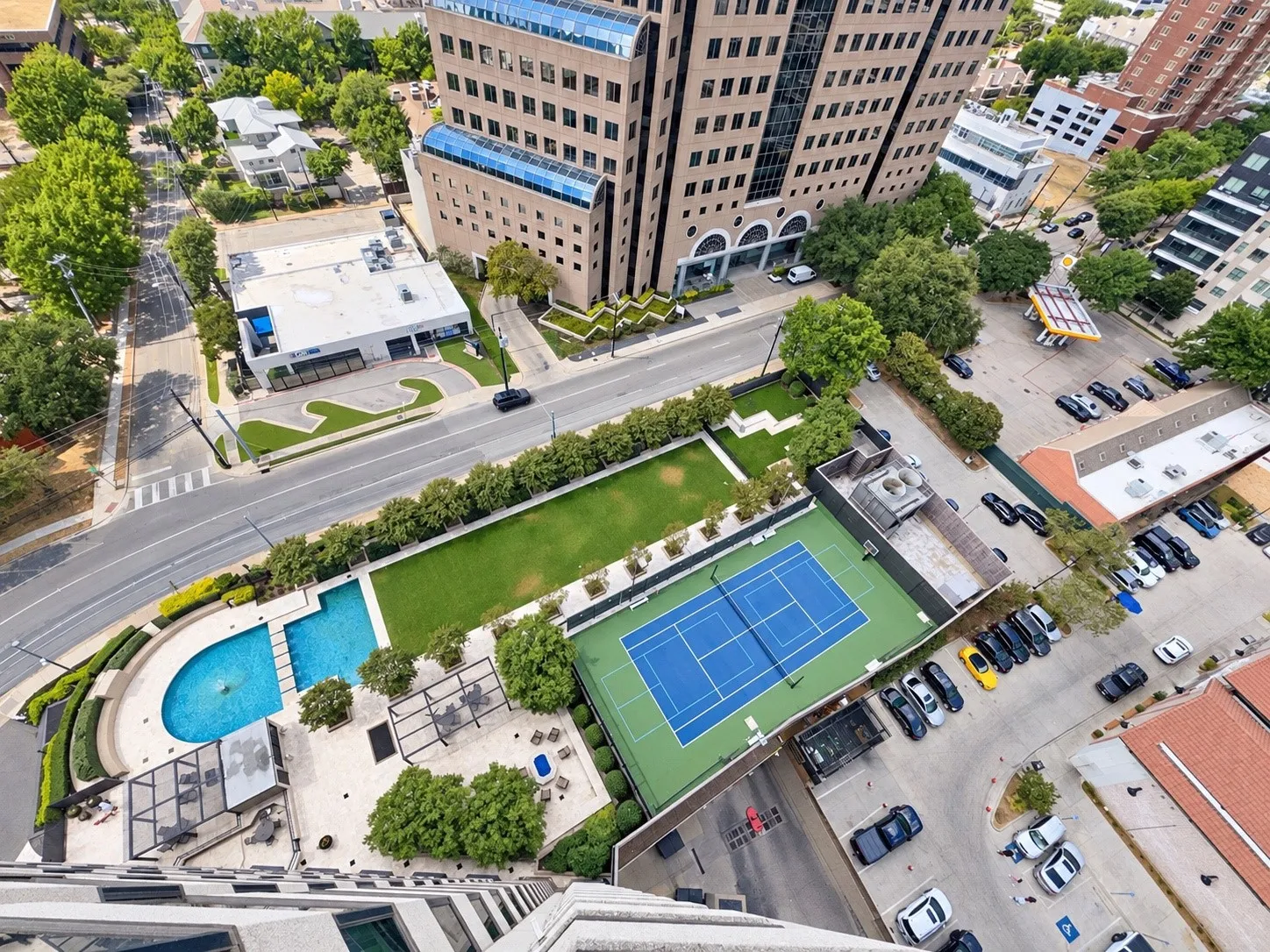 Resort-style pool with integrated spa, adjacent tennis court, manicured lawn area, and structured landscaping