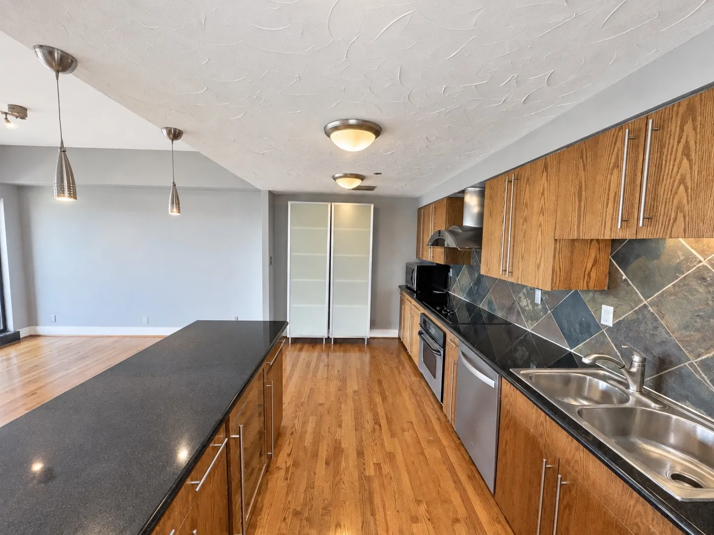 Kitchen featuring wood-finish cabinetry, dark countertops, a tile backsplash, and stainless-steel appliances