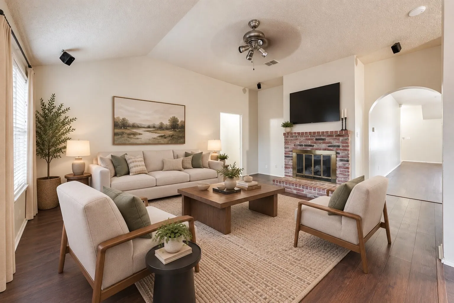 Vaulted ceiling with a ceiling fan, brick fireplace with a hearth, wood-finish flooring, and arched doorways