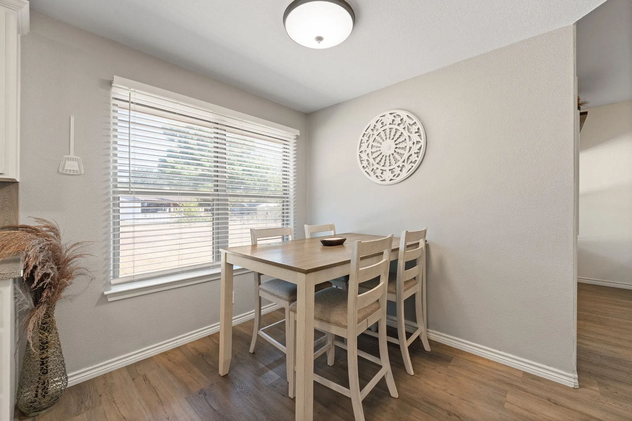 Wood-finish flooring, light gray wall paint, and a bright window with blinds