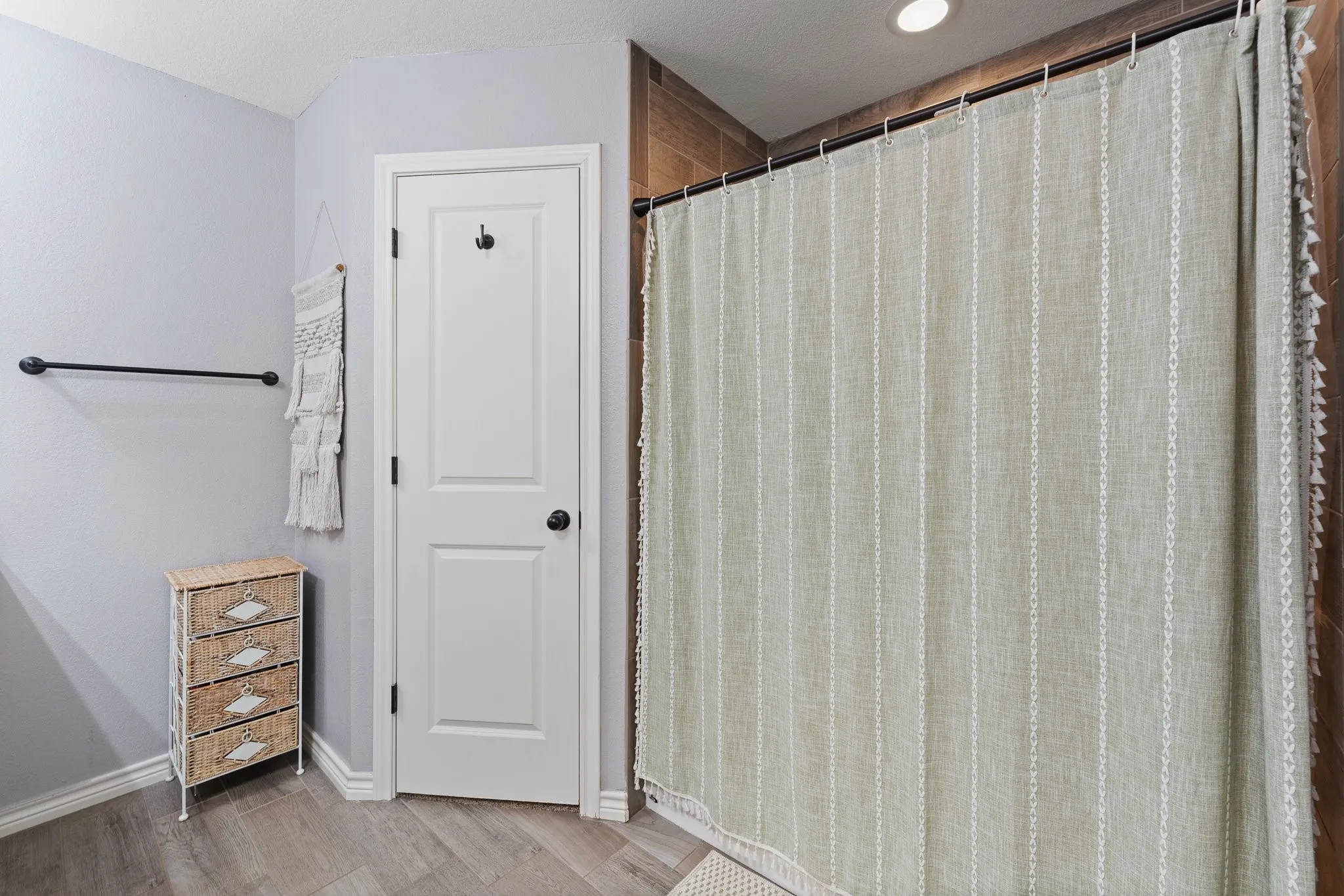 Recessed lighting, wood-finish flooring, white paneled door, and a dark-finish towel bar