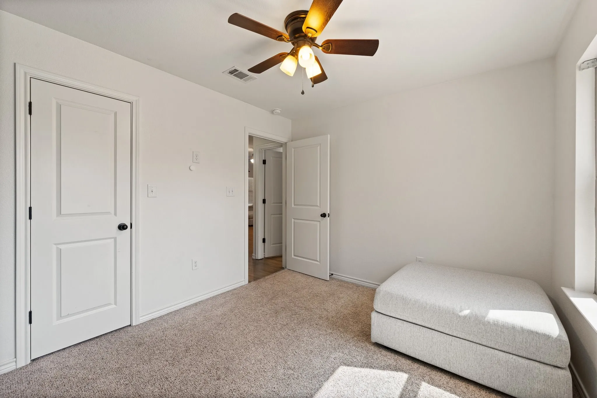 Plush carpet flooring, ceiling fan with integrated lighting, and multiple paneled doors