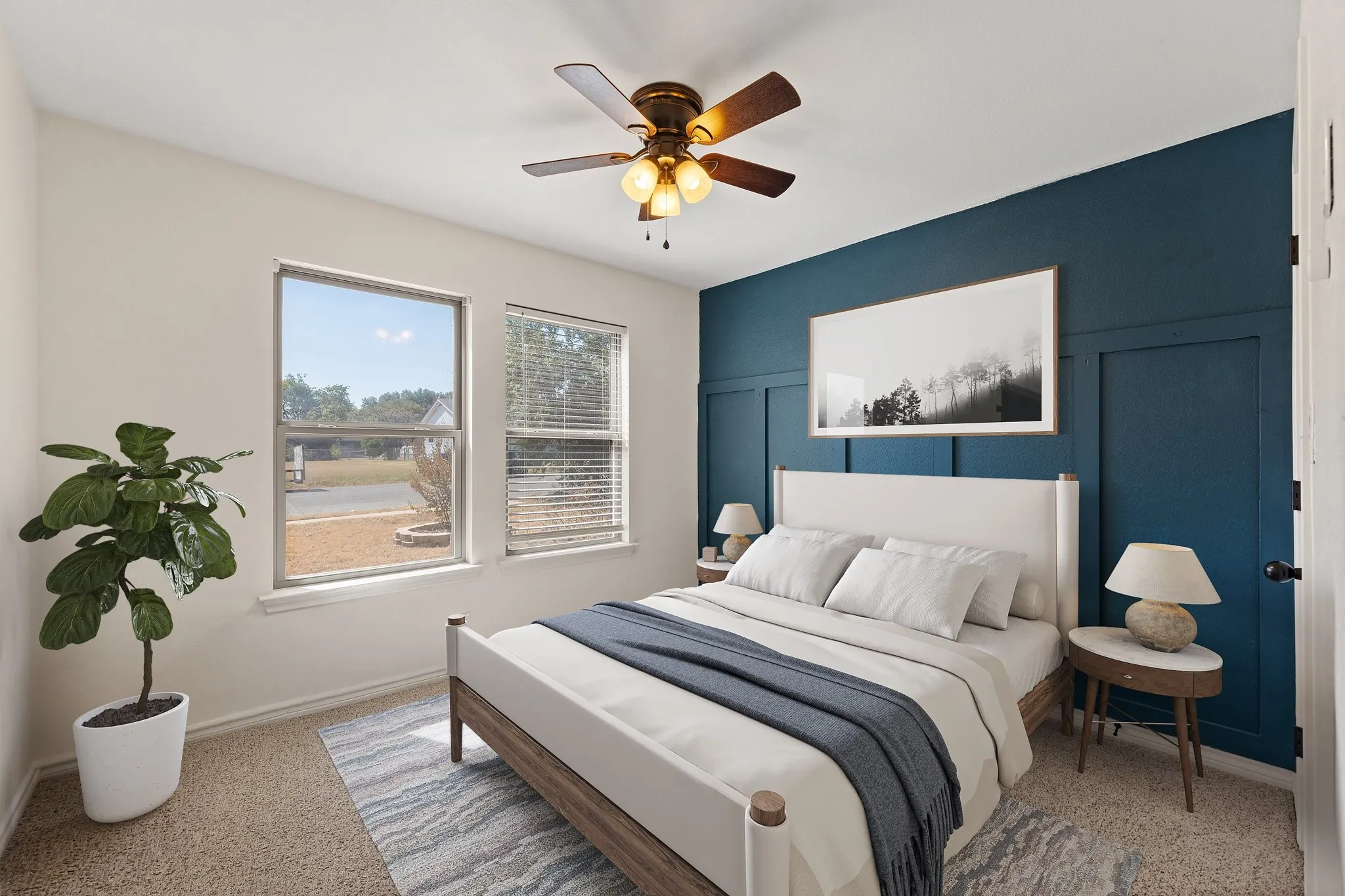 Two windows with blinds, ceiling fan with integrated lighting, accent wall with board and batten detailing, light-toned carpeting