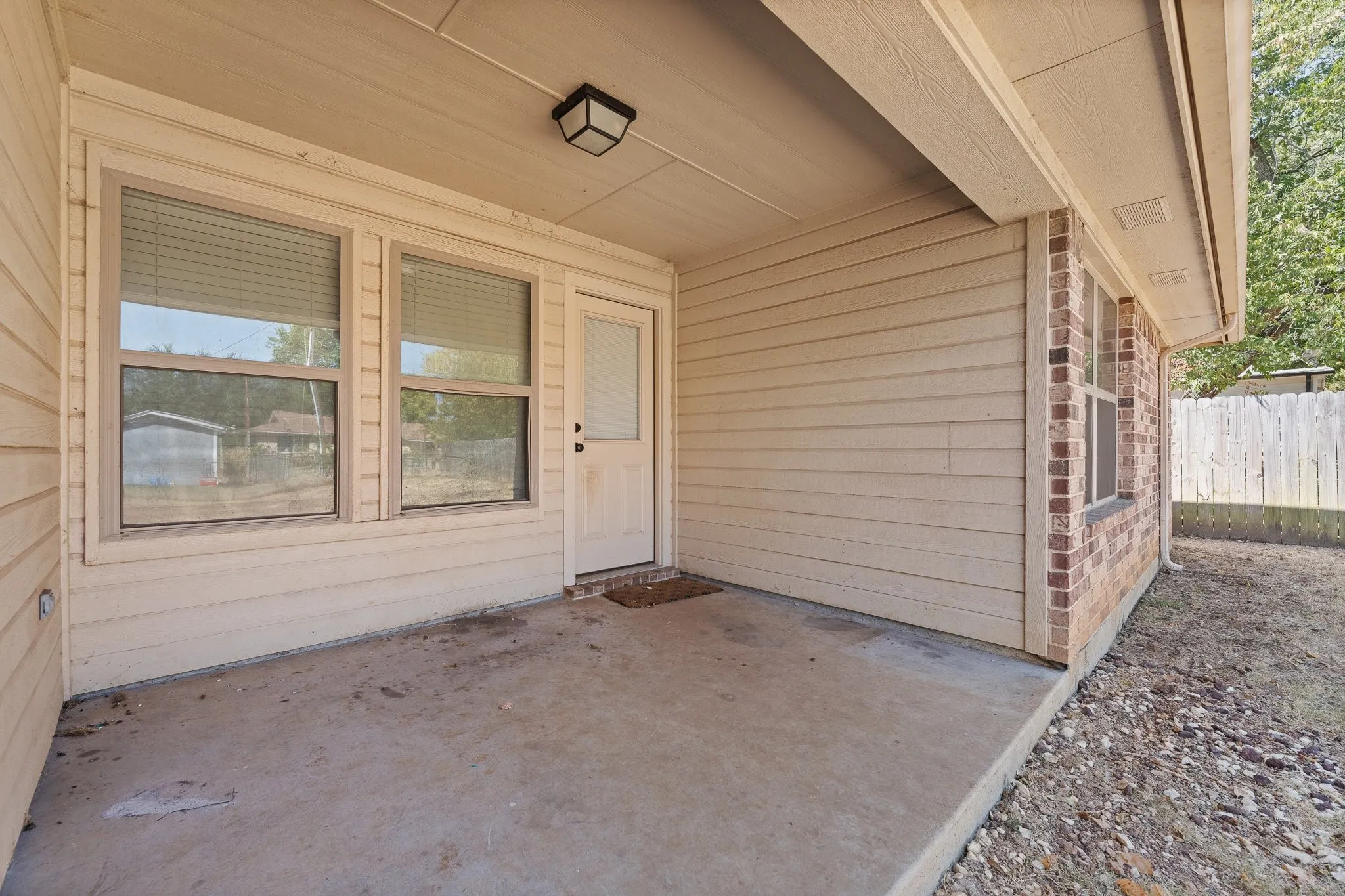 Covered concrete patio with siding and brick exterior