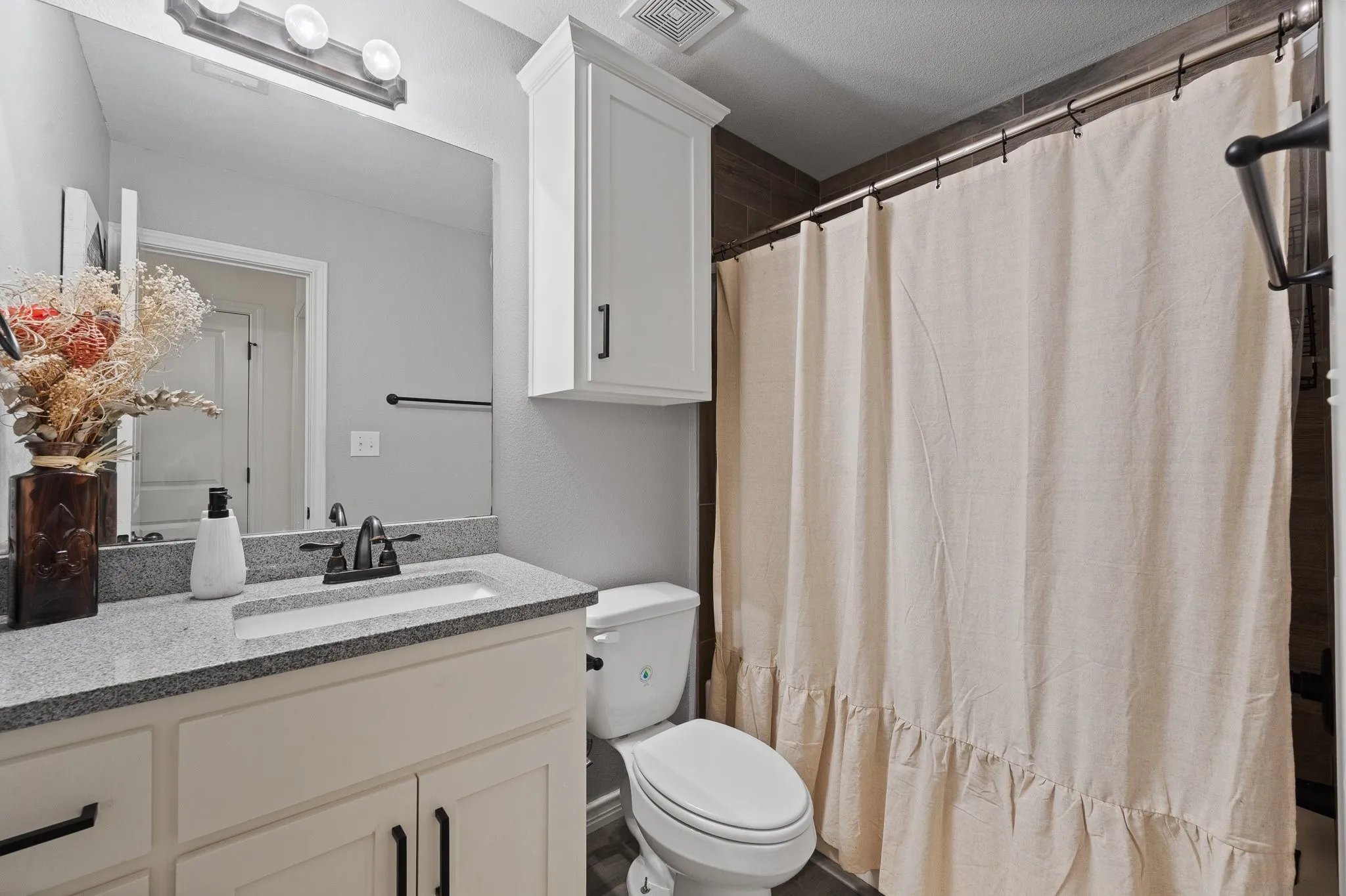 White vanity with black hardware, granite-style countertop, rectangular undermount sink, and black faucet