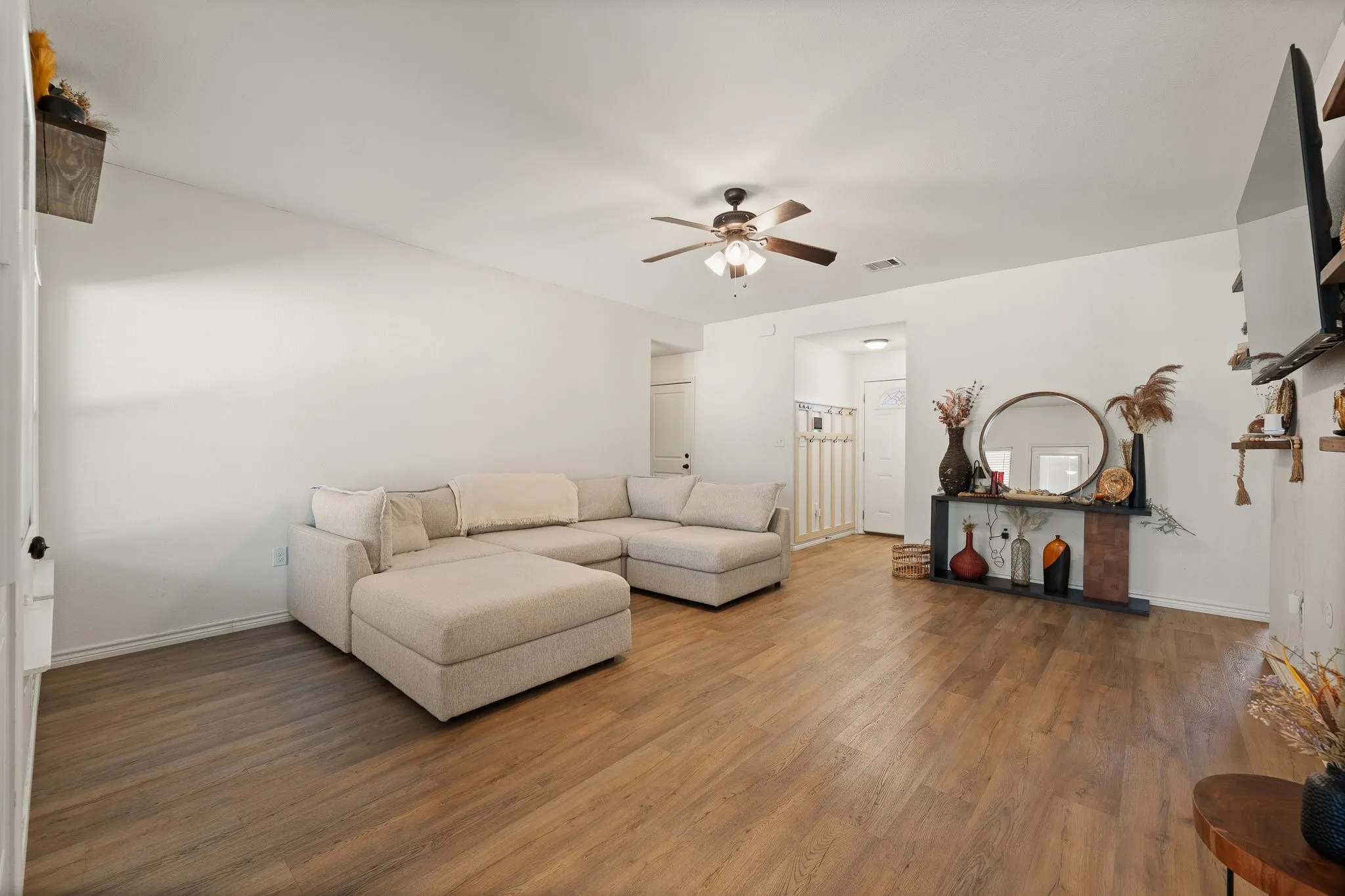Bright living space featuring wood-finish flooring, white walls, and a ceiling fan