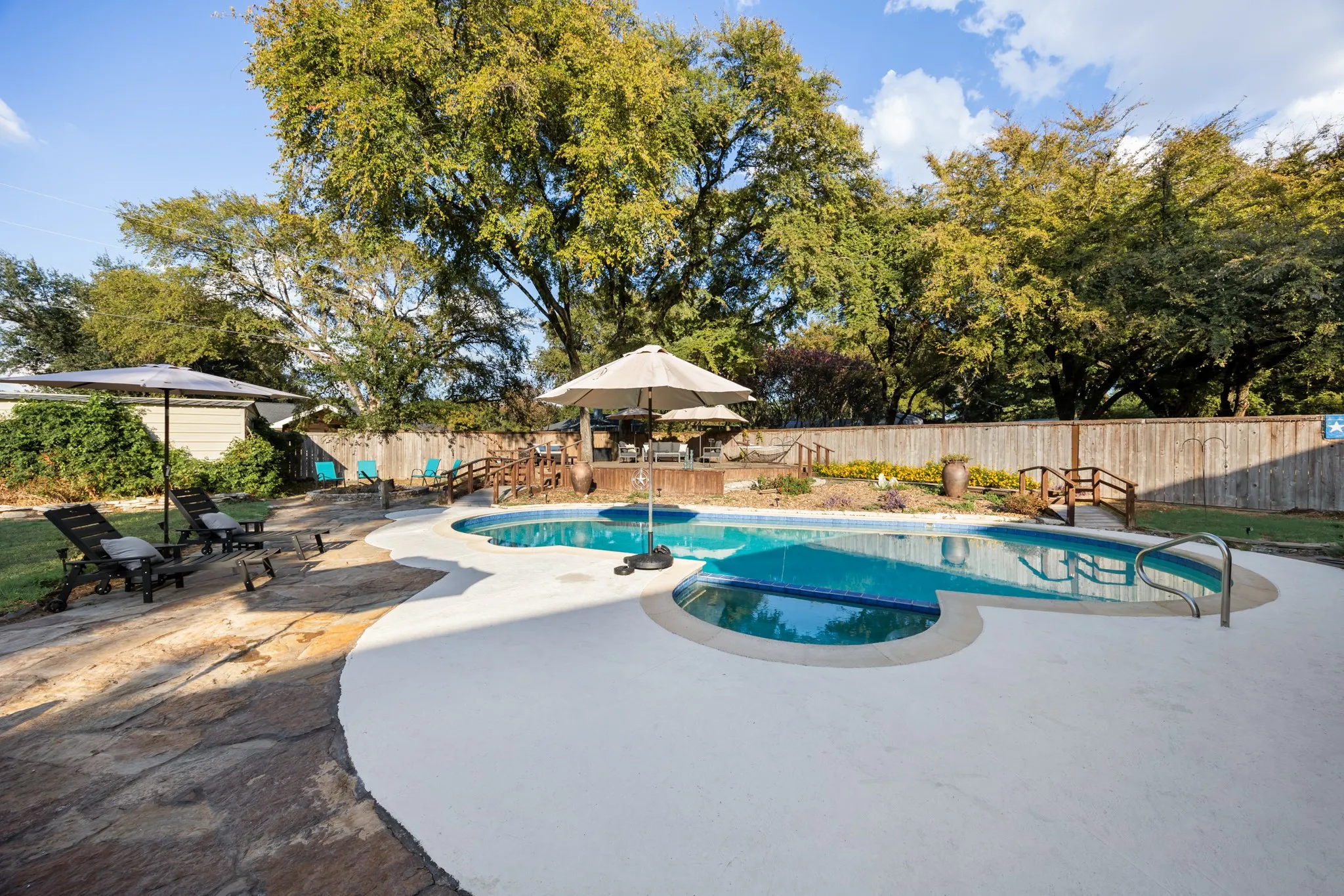 Resort-style pool with integrated spa, expansive deck, and surrounding stone patio