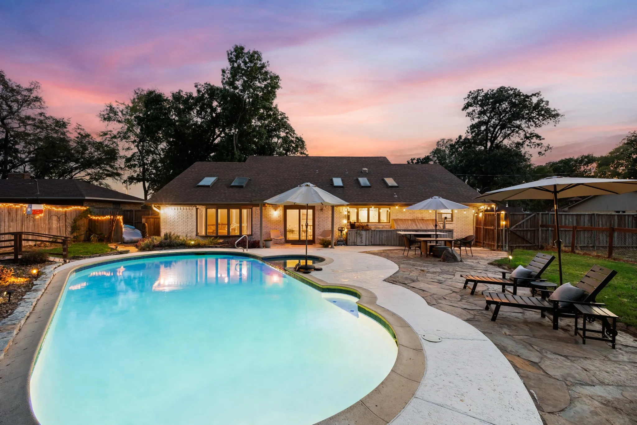 Expansive outdoor living area featuring a swimming pool, flagstone patio, and a dedicated outdoor kitchen space