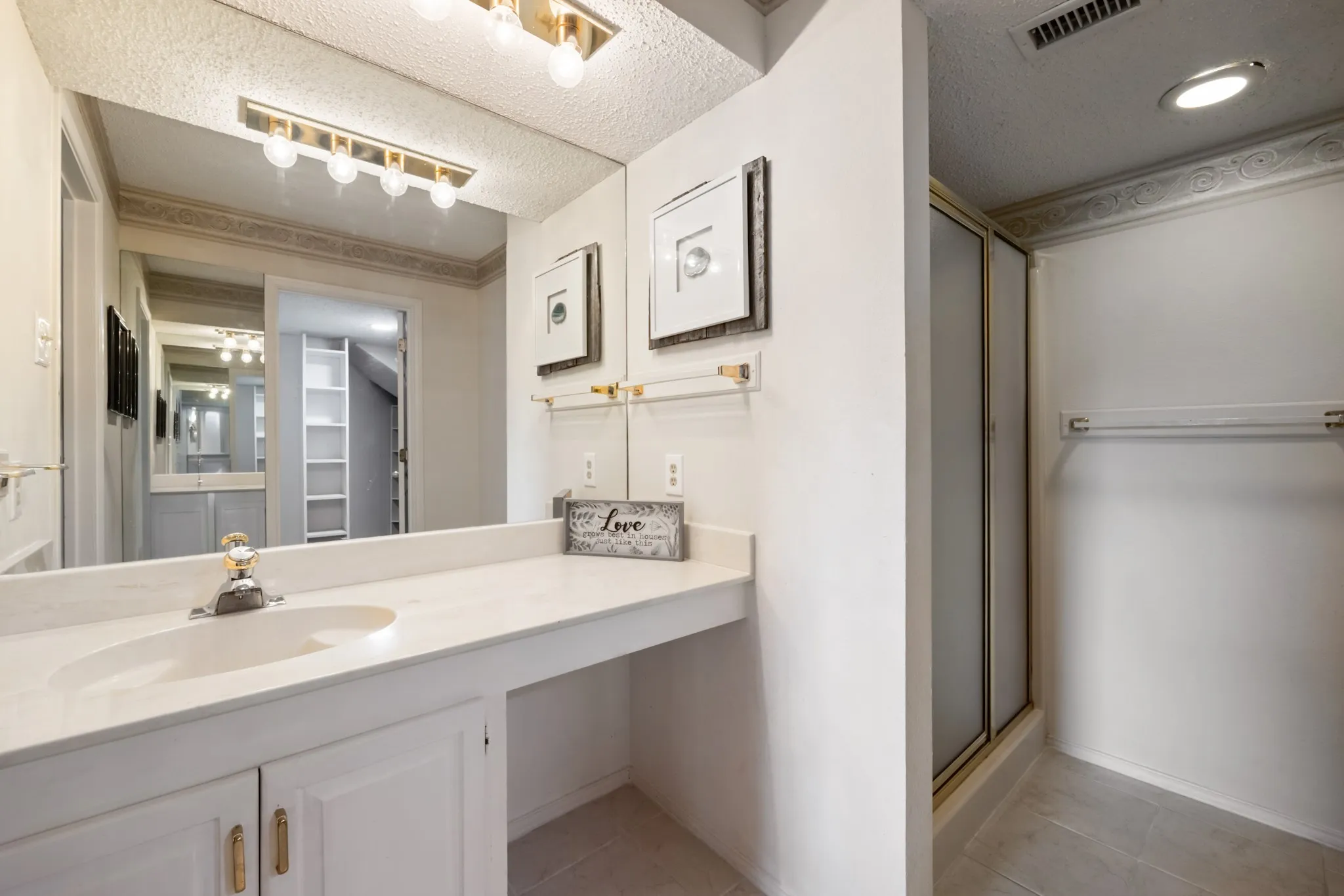 Vanity with integrated sink, gold-finish faucet, and expansive mirror