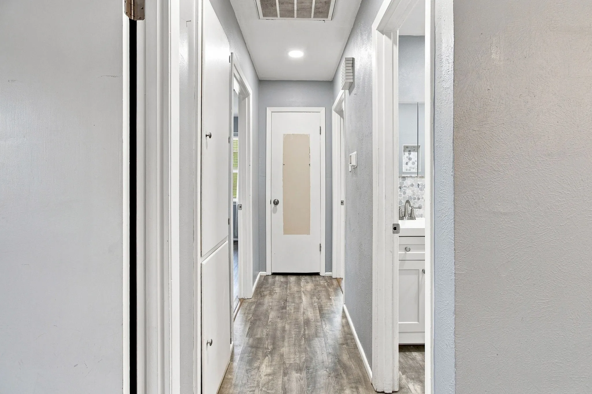 Wood-finish flooring with recessed lighting, paneled doors, and built-in cabinetry