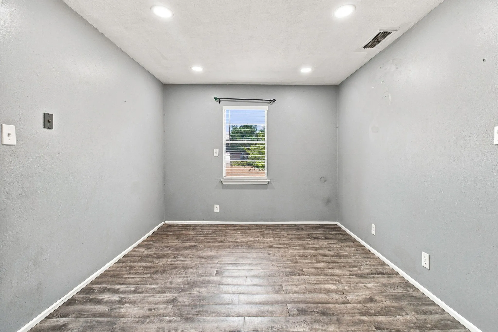 Recessed lighting, wood-finish flooring, and a window with blinds
