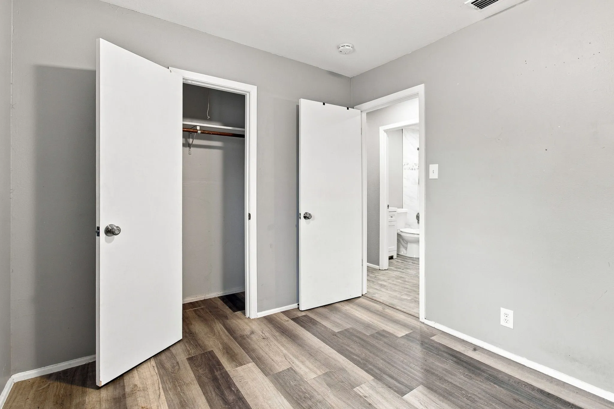 Wood-finish flooring throughout, bright white doors, and light gray wall paint