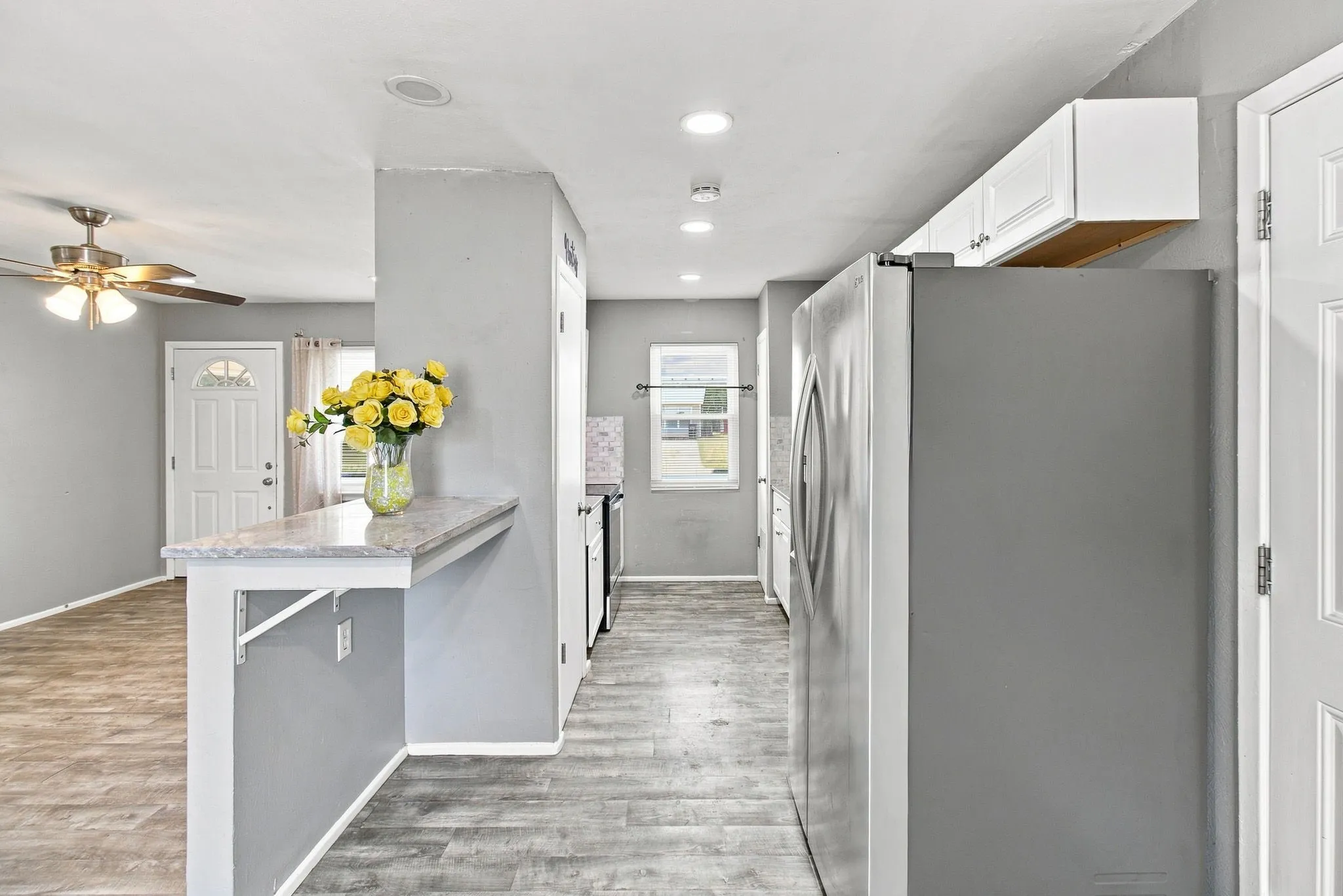 Open concept living space with recessed lighting, wood-finish flooring, and white cabinetry