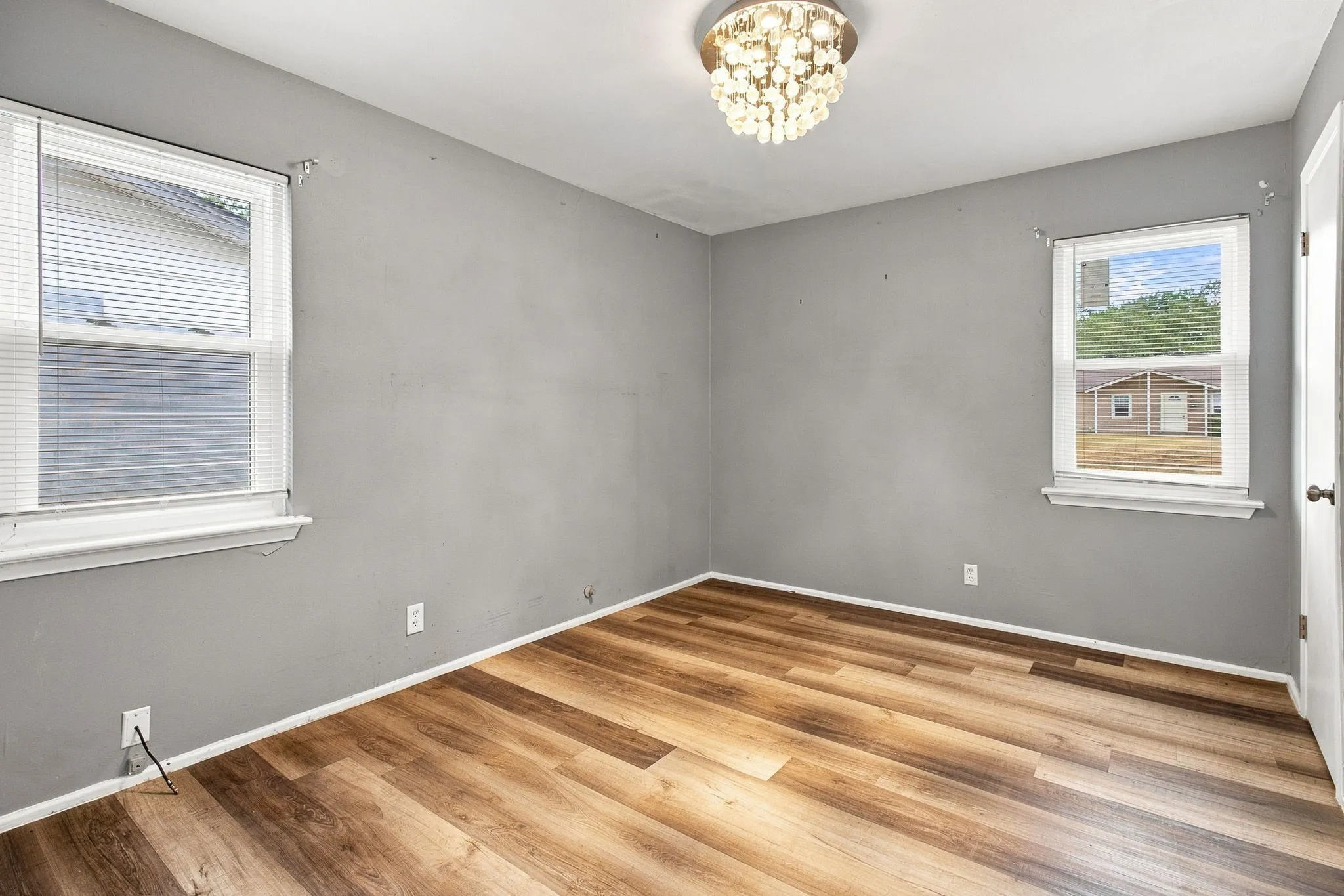 Wood-finish flooring, two windows, and a flush-mount light fixture