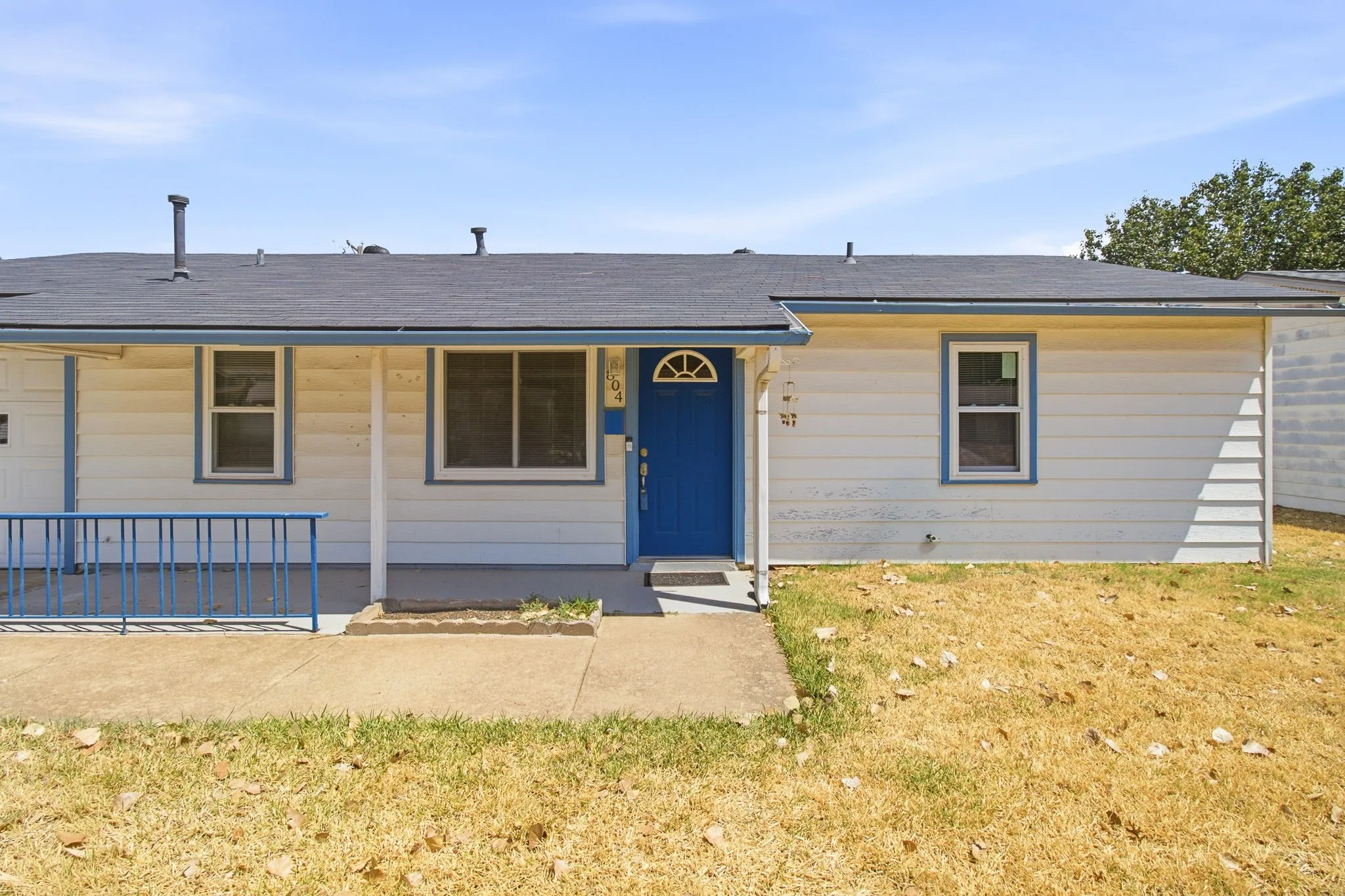 White siding exterior with a blue entry door, dark roof, and covered porch