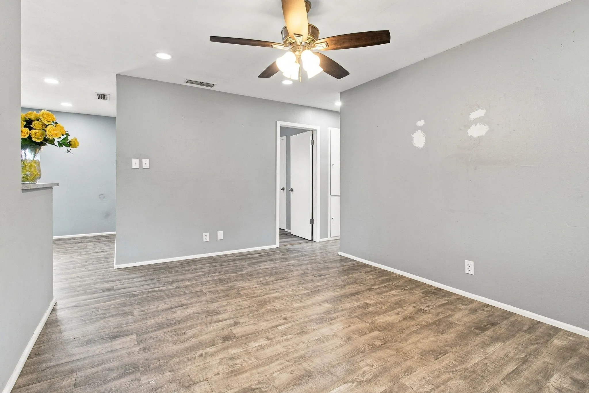 Wood-finish flooring with a ceiling fan light fixture and recessed ceiling lighting