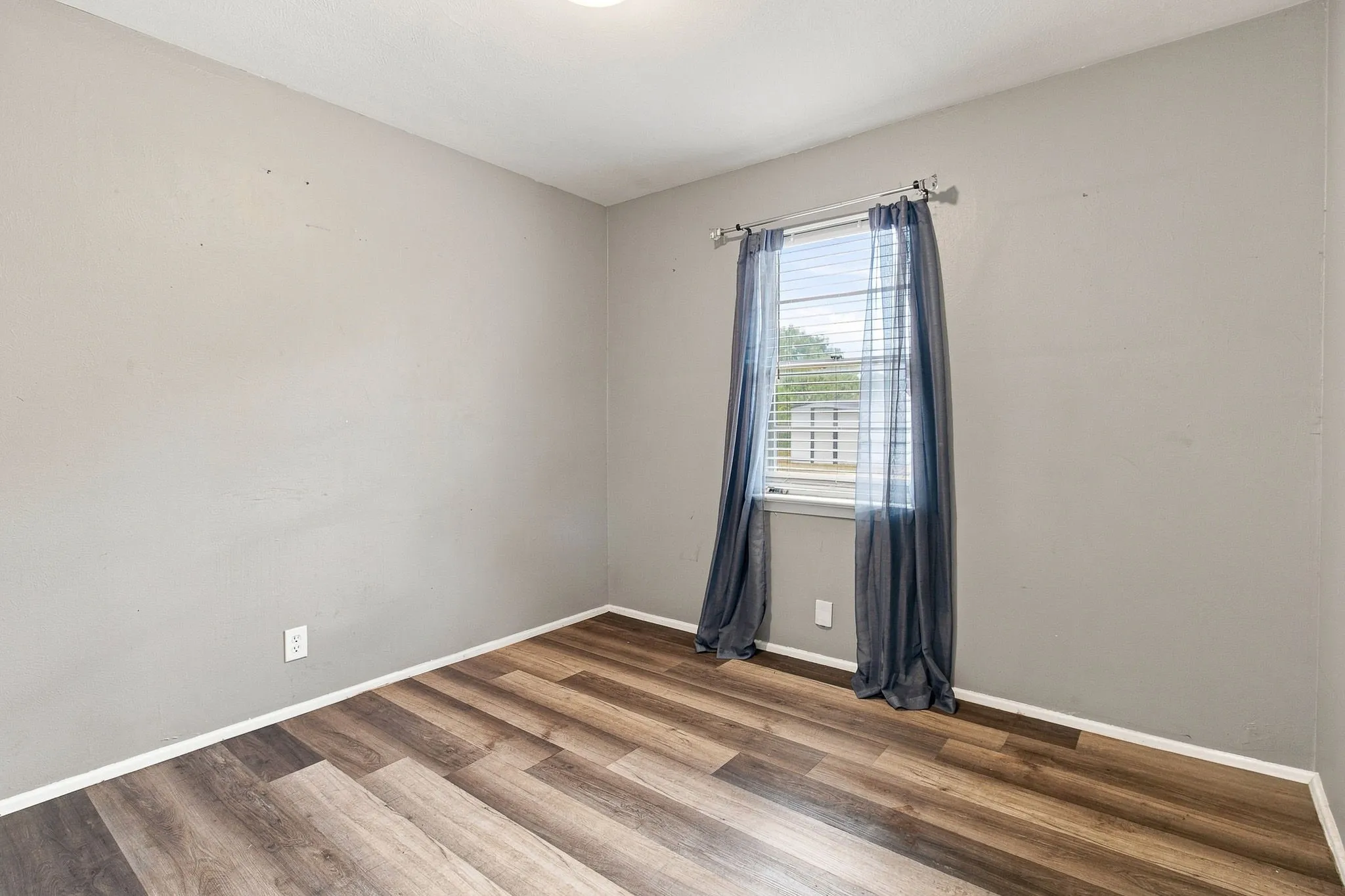 Wood-finish plank flooring, neutral wall tones, and a window with blinds