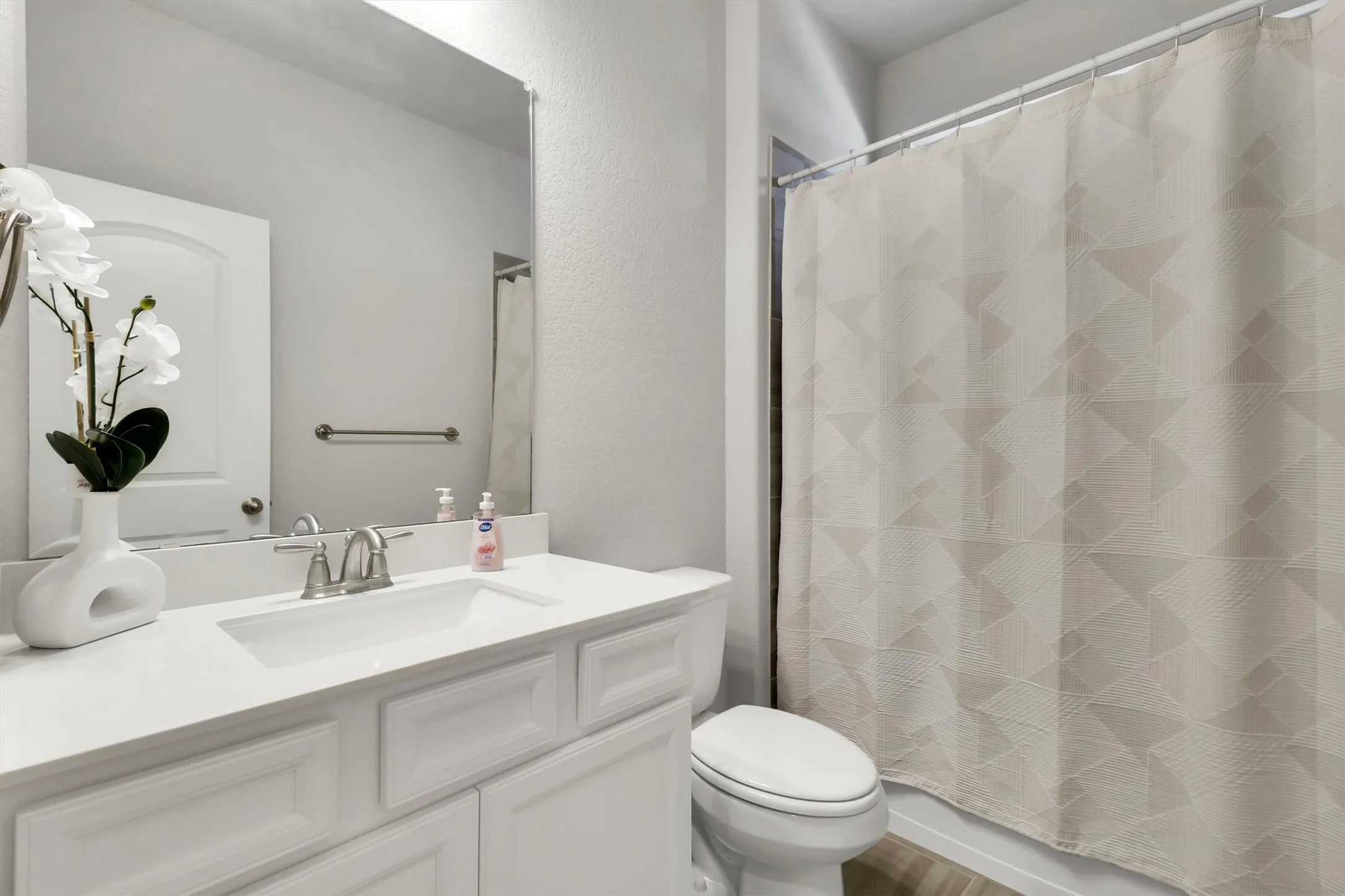 White vanity with an integrated sink, brushed nickel faucet, and a large wall-mounted mirror