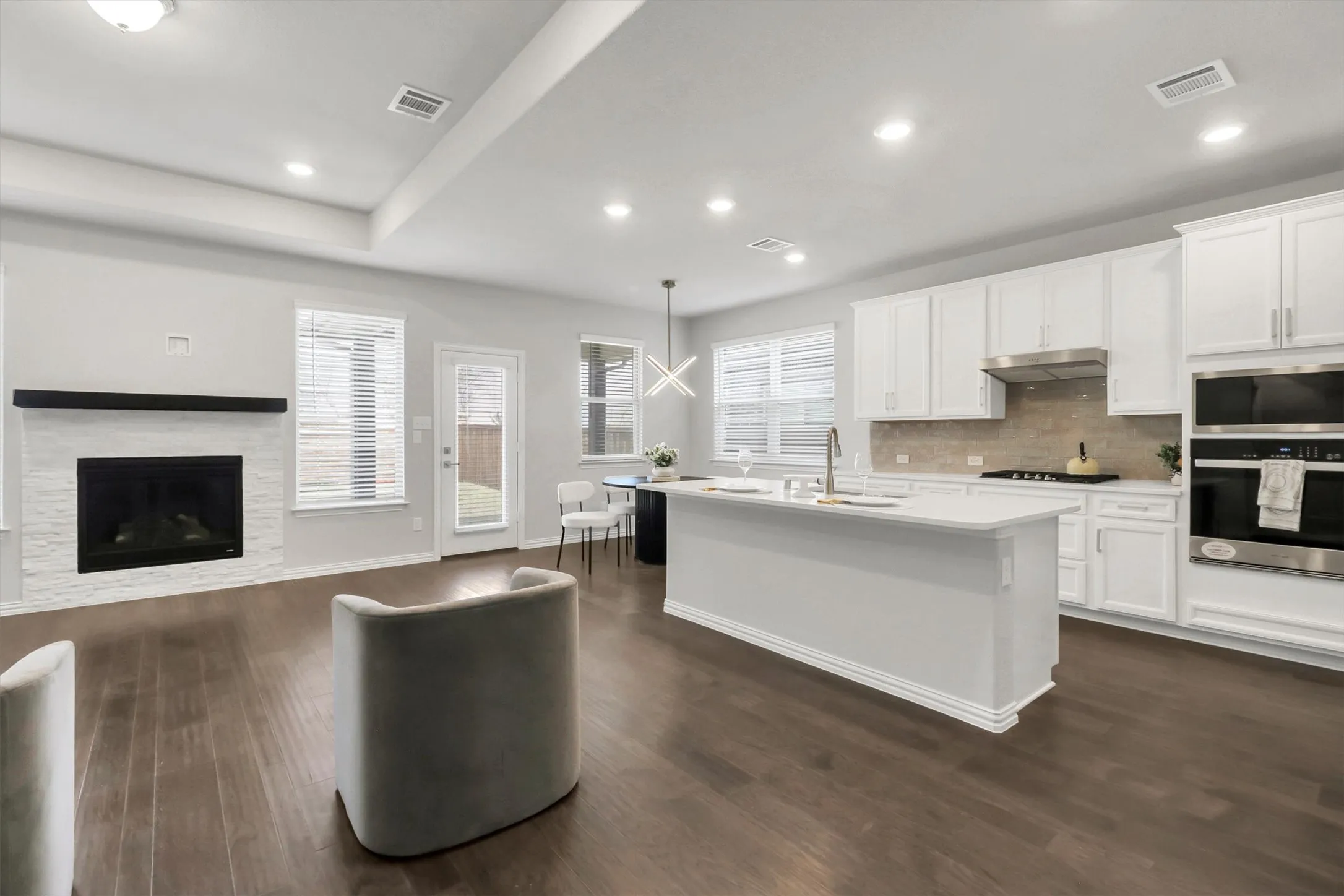 Living Room Open-concept living space featuring wood-finish flooring, a white brick fireplace with a dark mantel, and recessed lighting