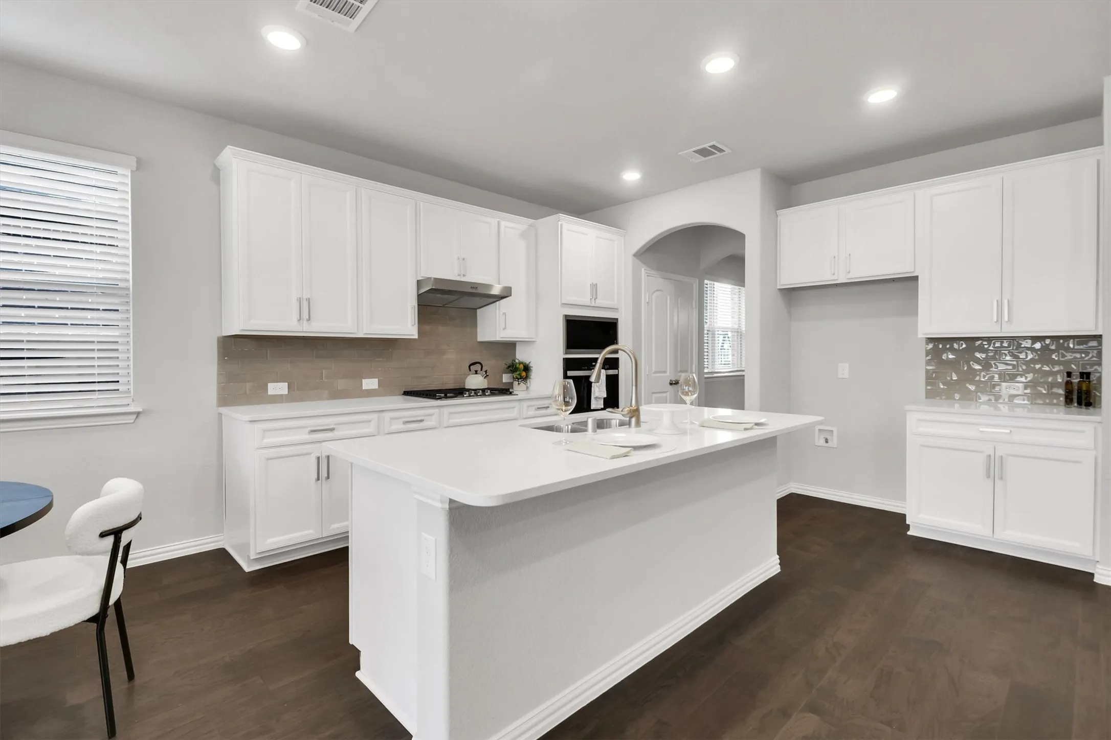 Bright kitchen with white cabinetry, a center island, dark wood-finish flooring, and built-in stainless steel appliances