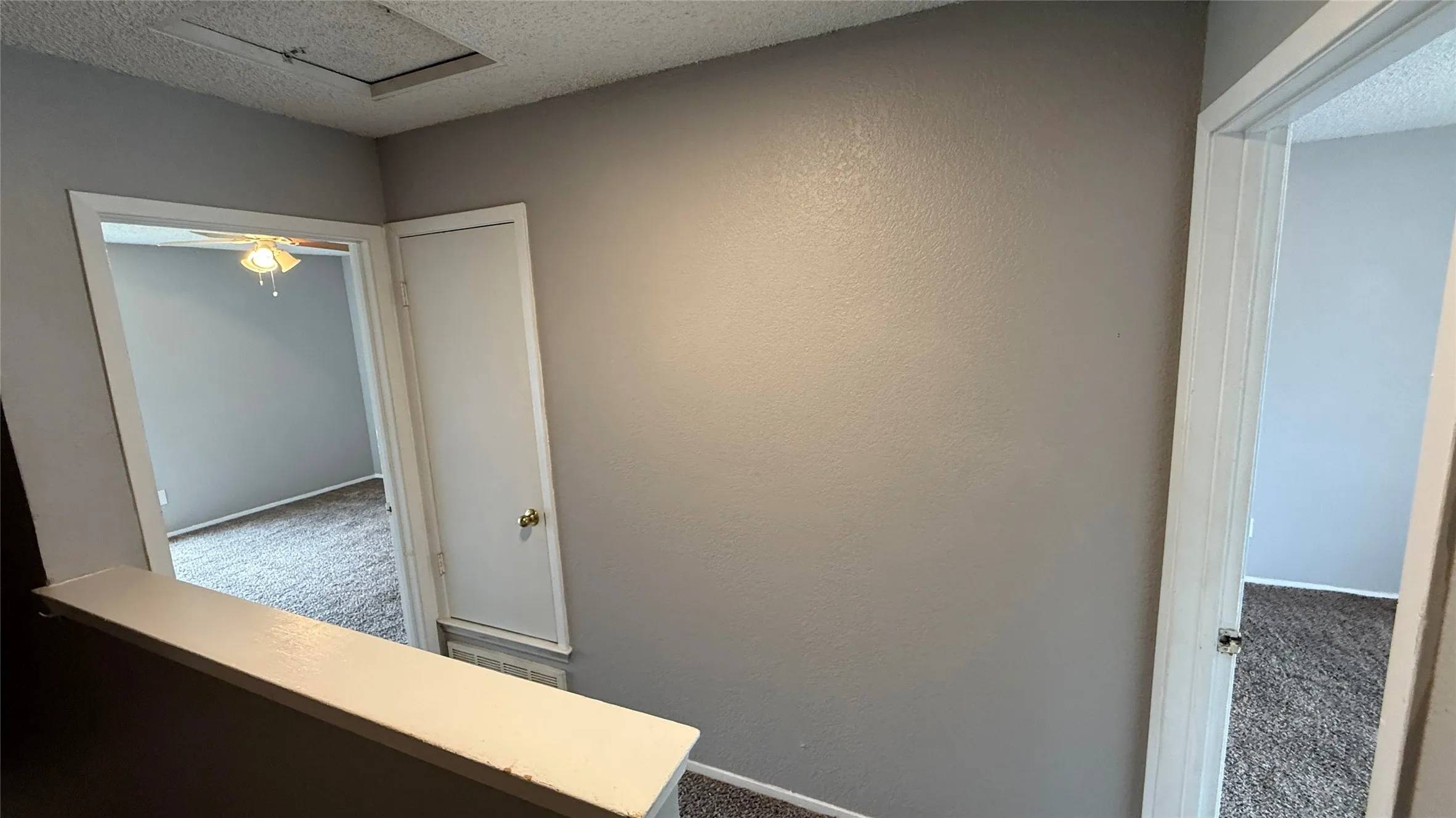 Hallway featuring baseboards, carpet flooring, a textured wall, and a textured ceiling