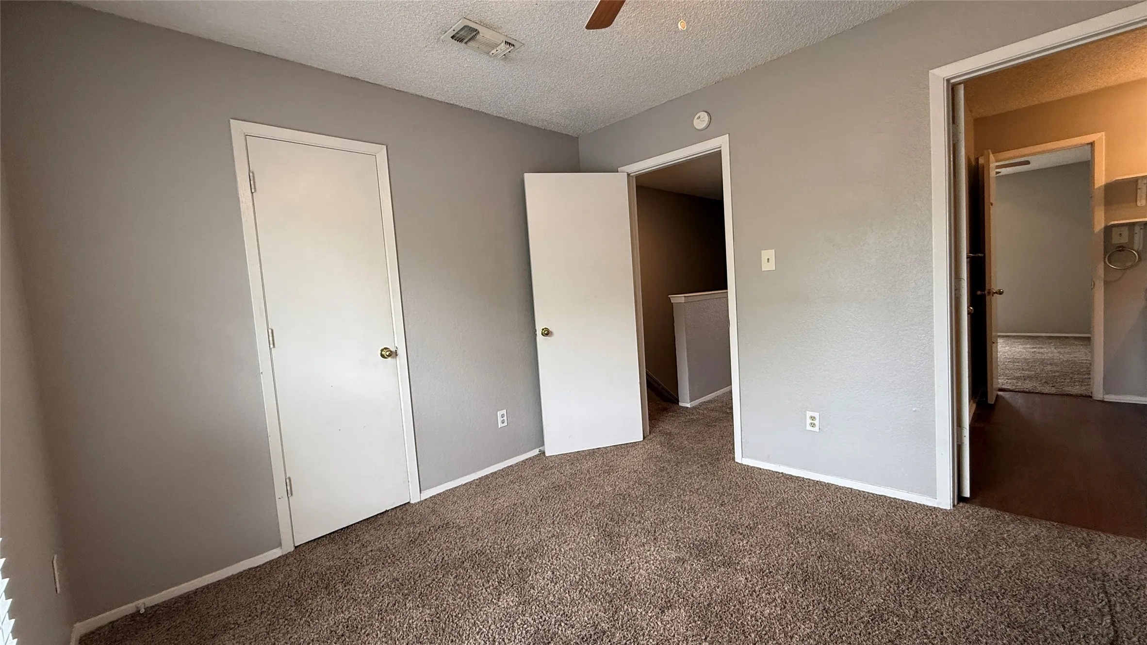 Unfurnished bedroom featuring ceiling fan, carpet, a textured ceiling, visible vents, and baseboards