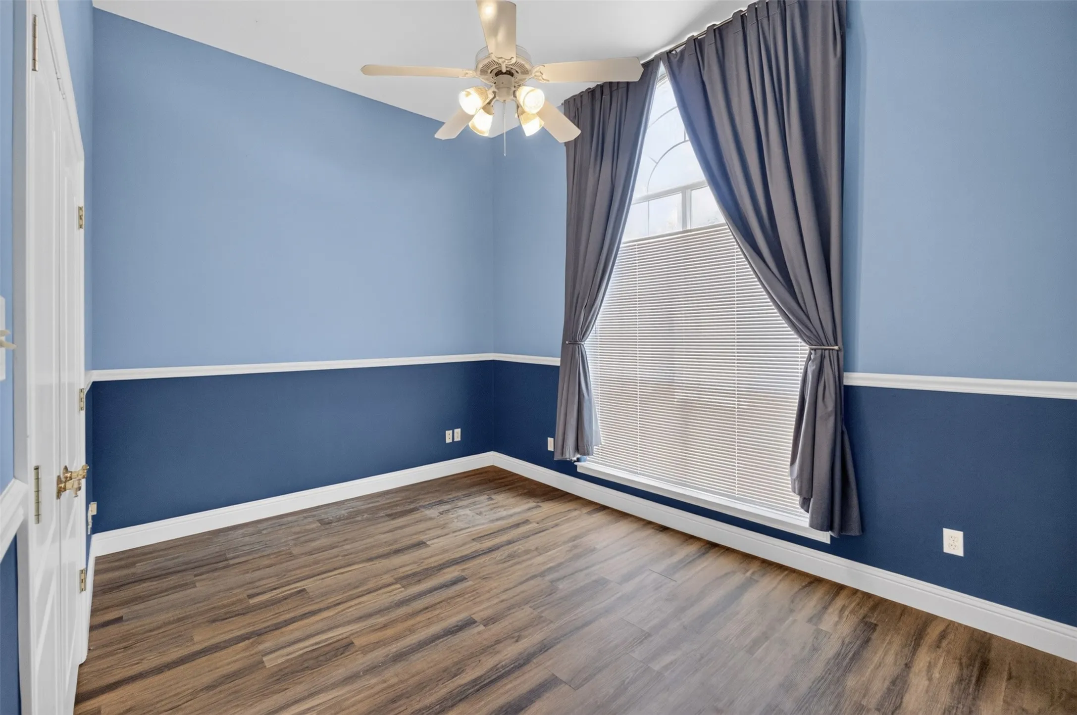 Wood-finish flooring, two-tone wall treatment, and an arched window.