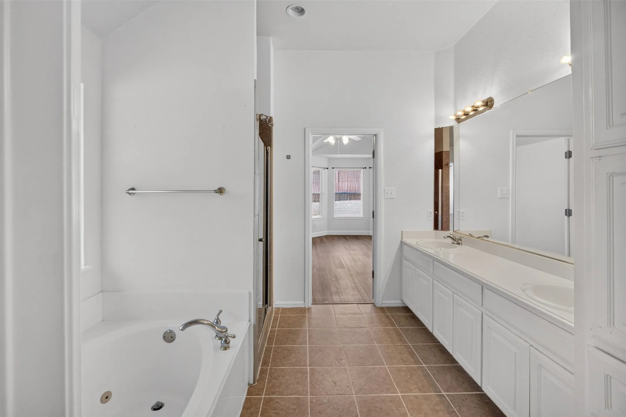 Dual sink vanity with white cabinetry, tile flooring, built-in bathtub, and an integrated shower enclosure. Master bathroom.