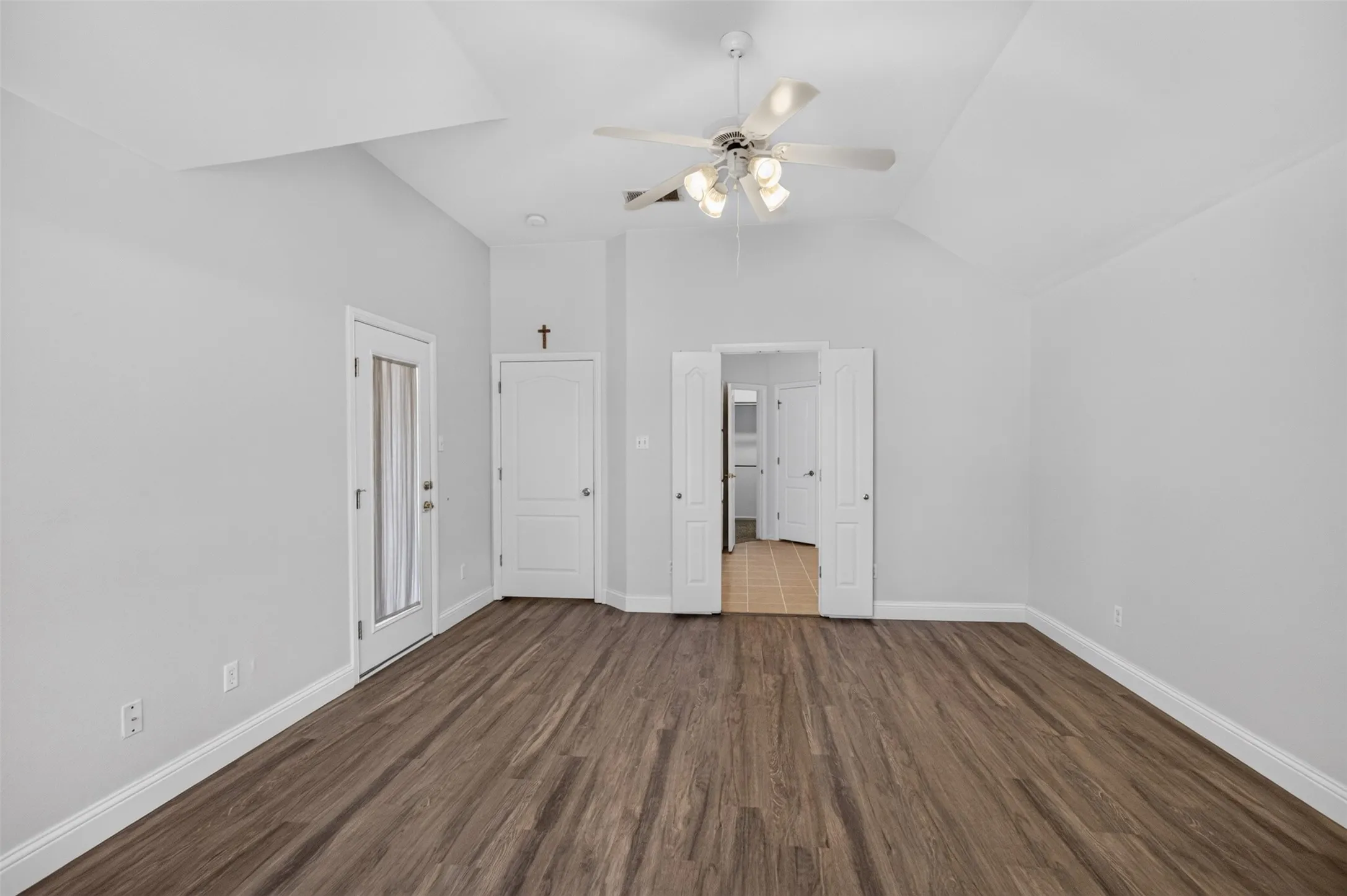 Vaulted ceiling with a ceiling fan, wood-finish flooring, and white interior doors