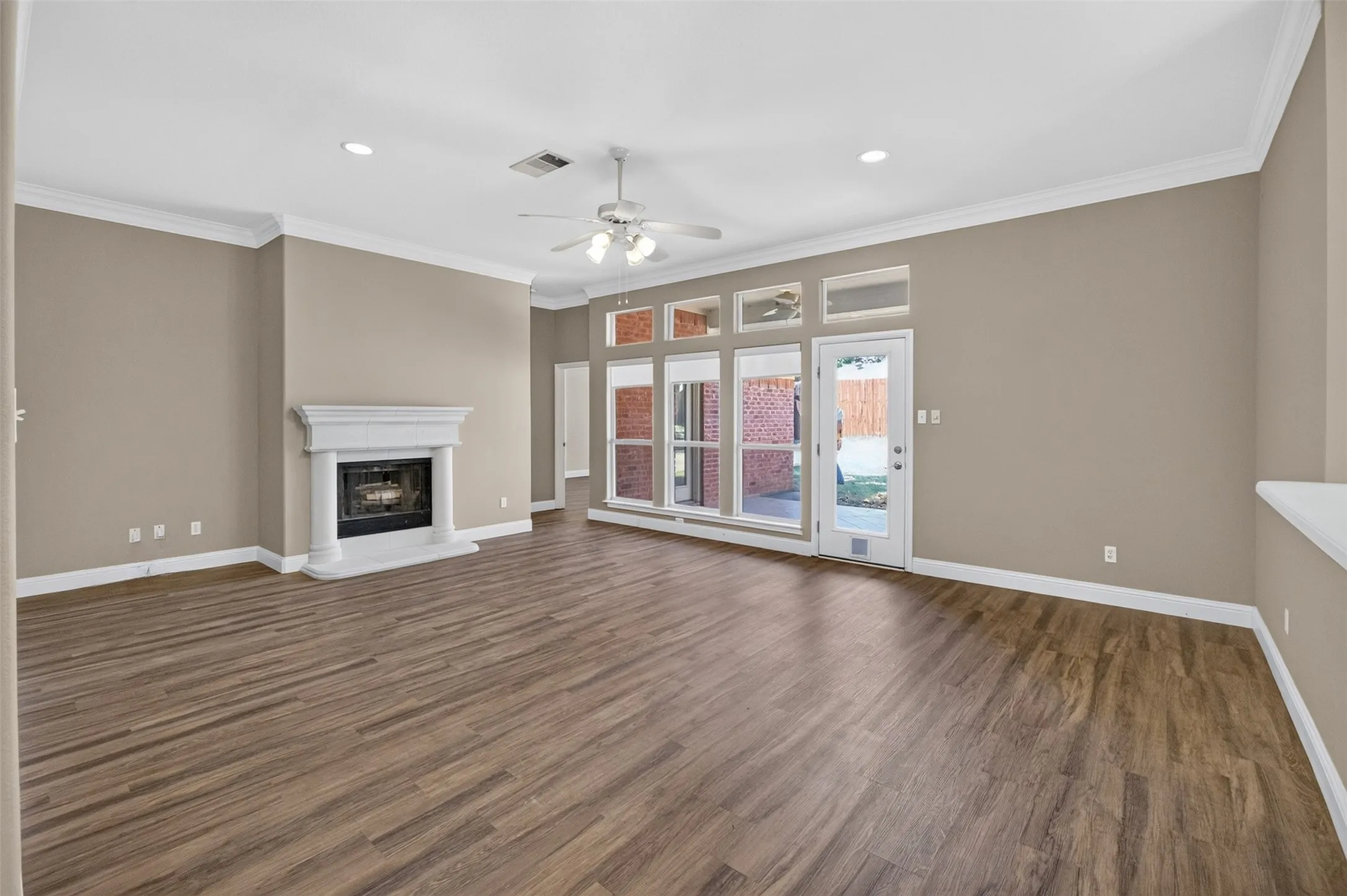 Spacious room featuring wood-finish flooring, a decorative fireplace with a stone surround, recessed lighting, and a ceiling fan