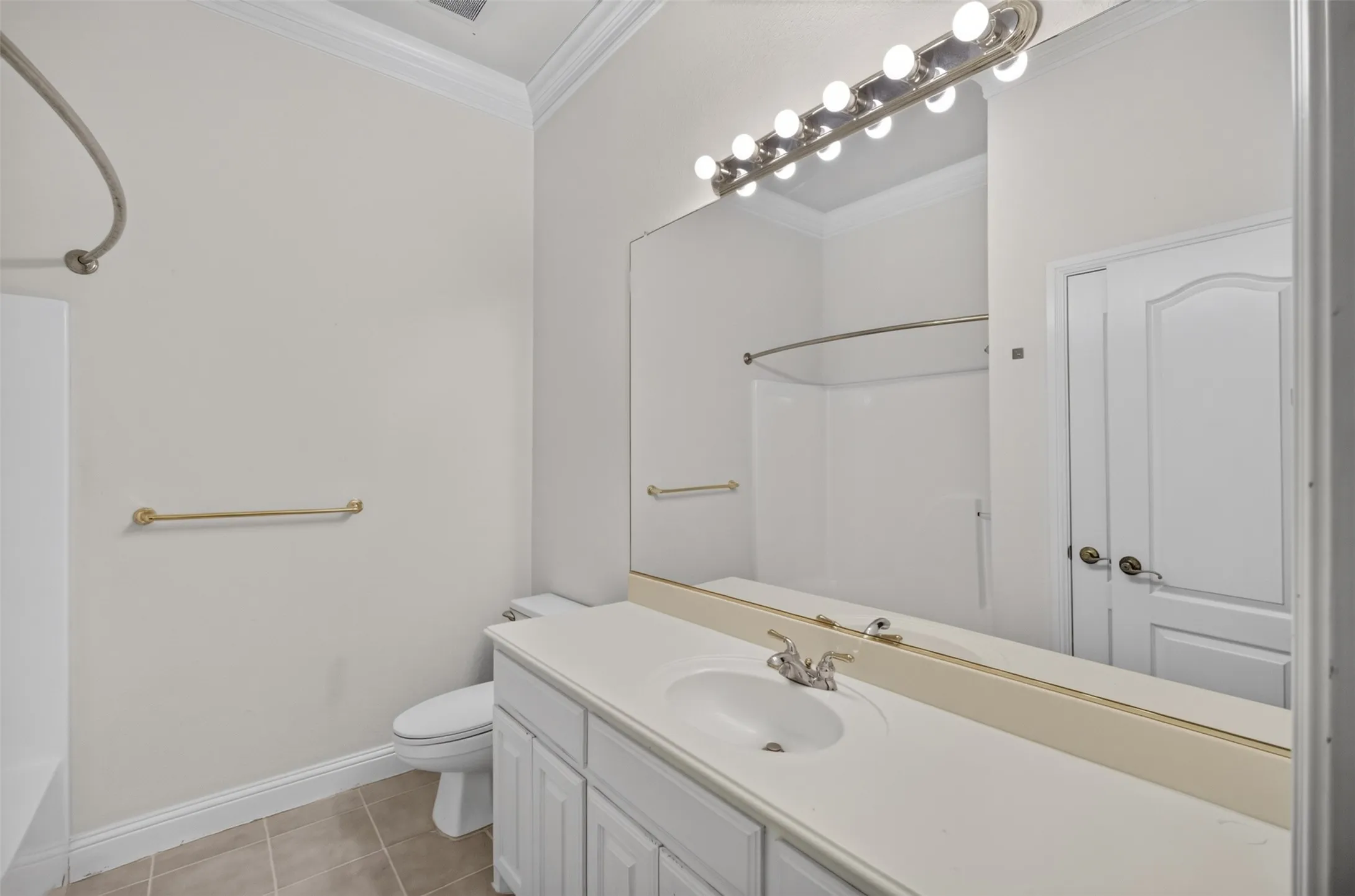 White vanity with an integrated sink, large wall-mounted mirror, and overhead vanity lighting.