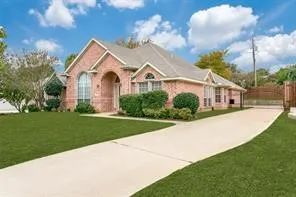 Brick exterior with arched entry, arched windows, gabled roofline, concrete driveway, and manicured landscaping. Private gated driveway  with enough room for a boat or a RV.
