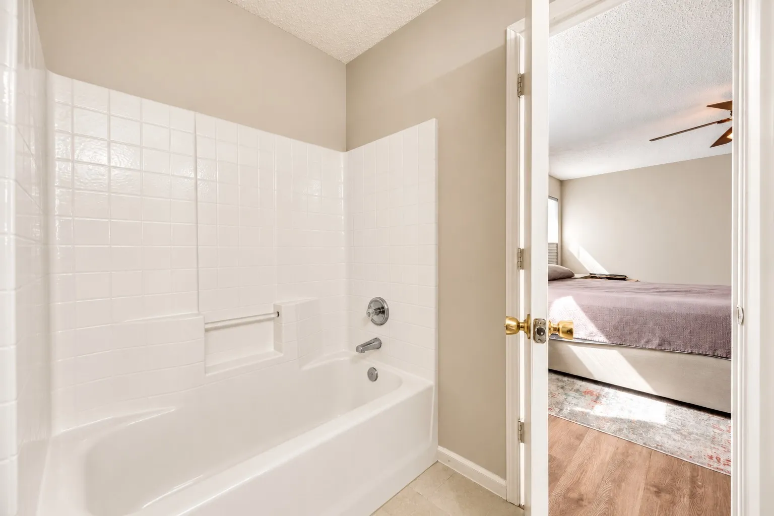Tub and shower combination with white subway tile surround and integrated soap dish