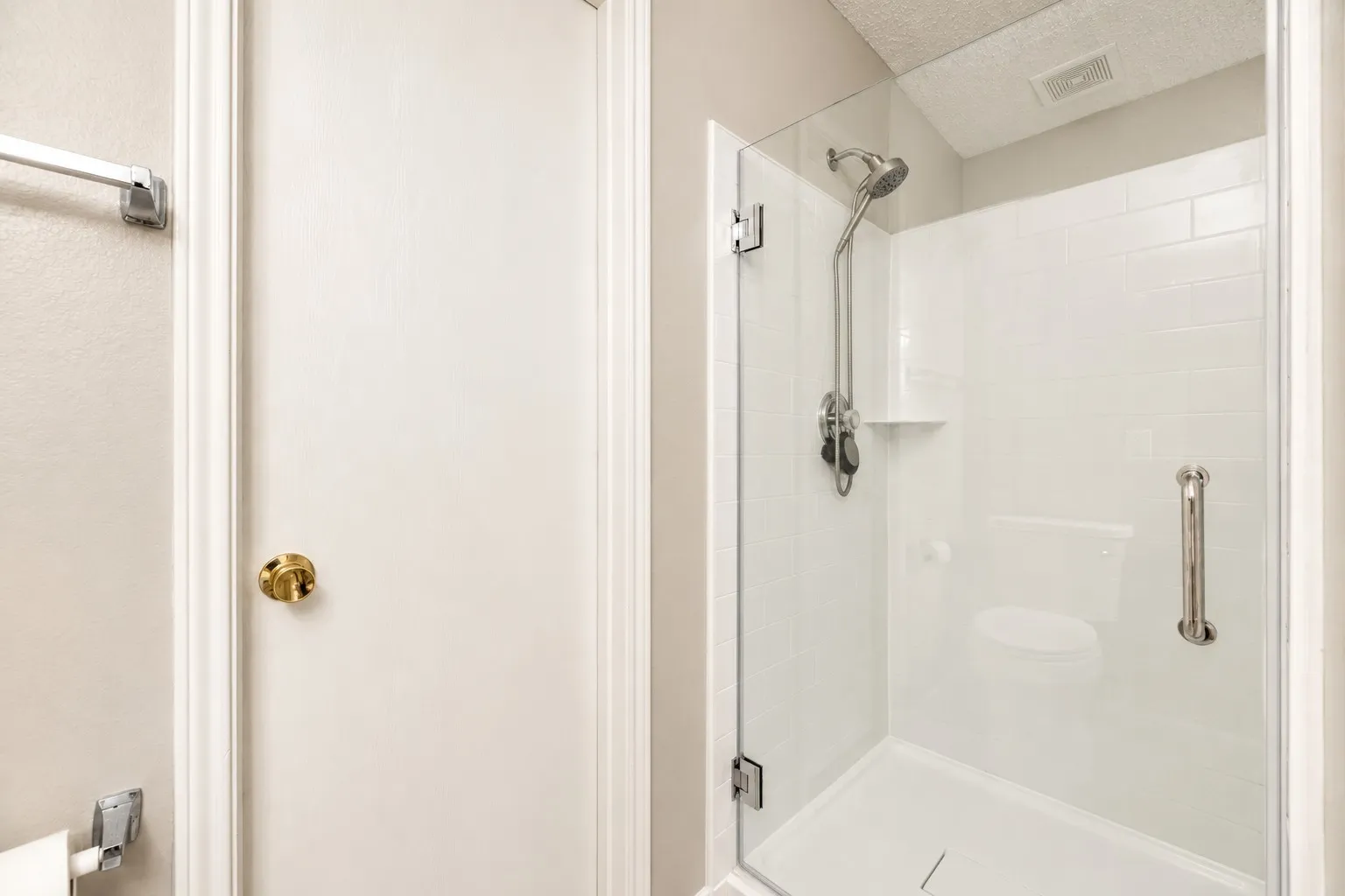 Glass-enclosed shower with subway tile surround, built-in shelf, and brushed nickel fixtures