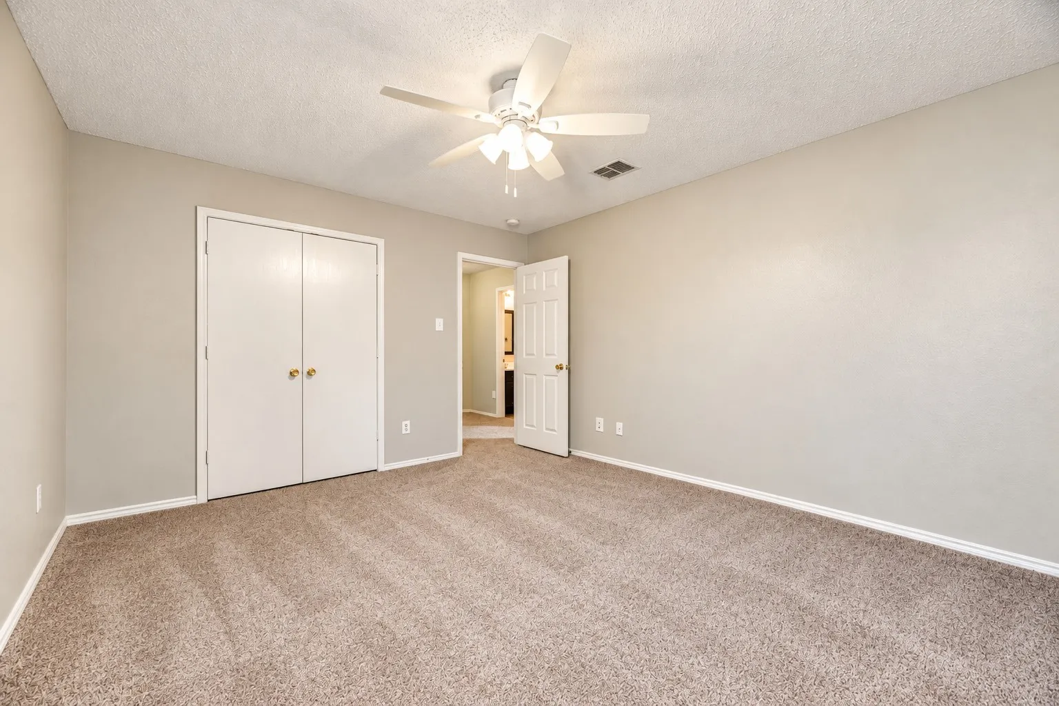 Spacious room featuring neutral wall tones, textured ceiling, and carpeted flooring